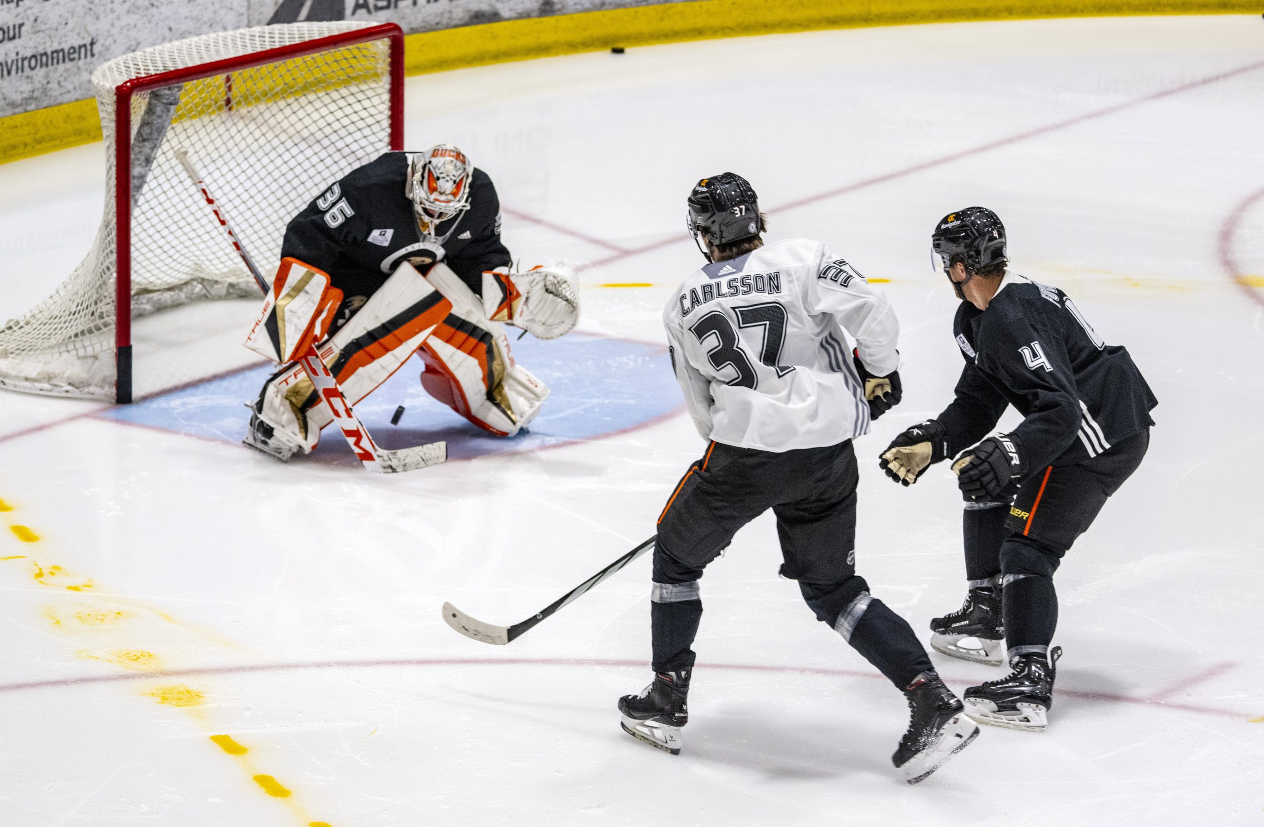 Ducks goaltender John Gibson, left, looks for the puck following...