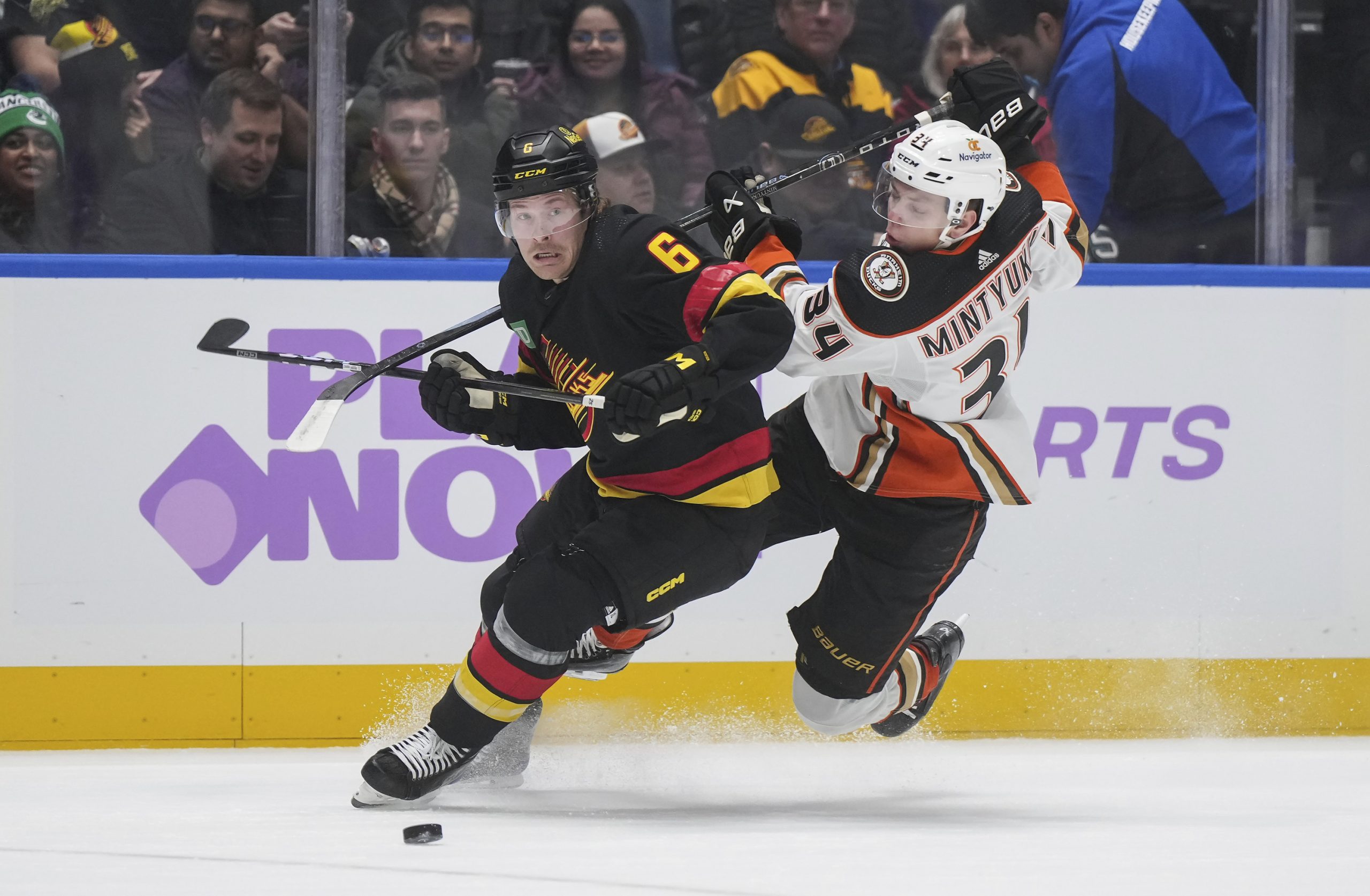 The Ducks’ Pavel Mintyukov, right, falls while checking the Vancouver...