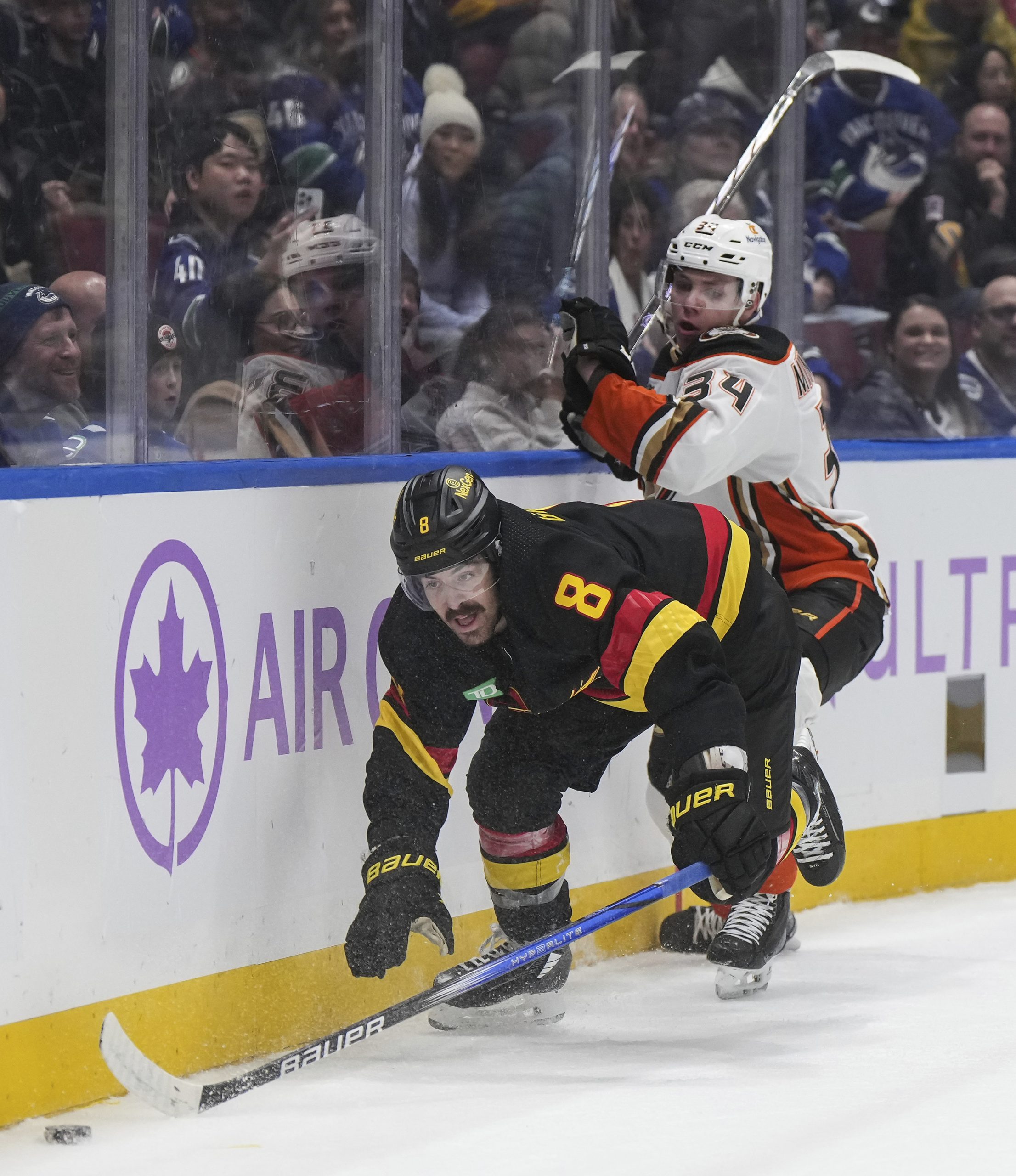 The Vancouver Canucks’ Conor Garland, left, is checked by the...