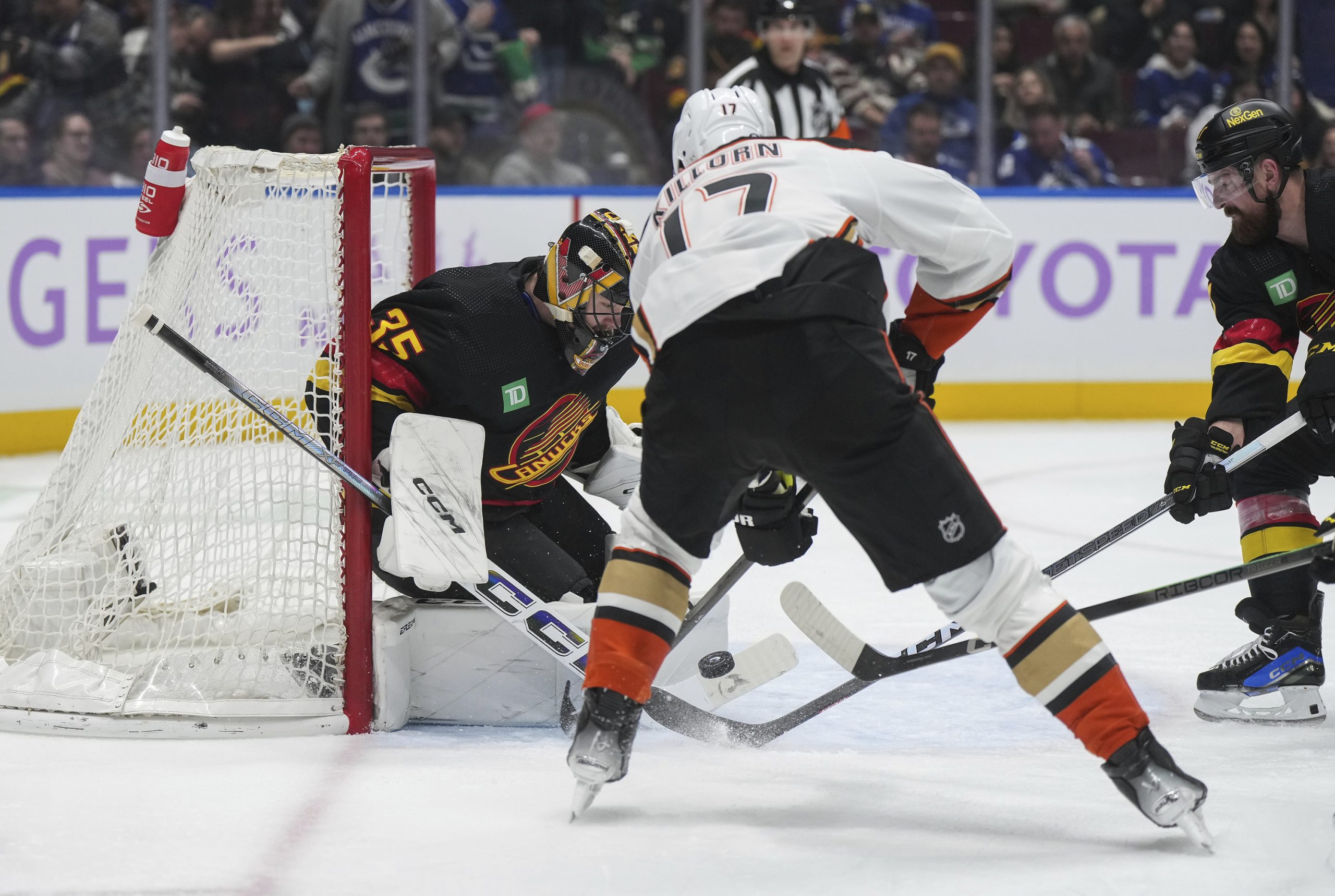 Vancouver Canucks goalie Thatcher Demko, back left, stops a shot...