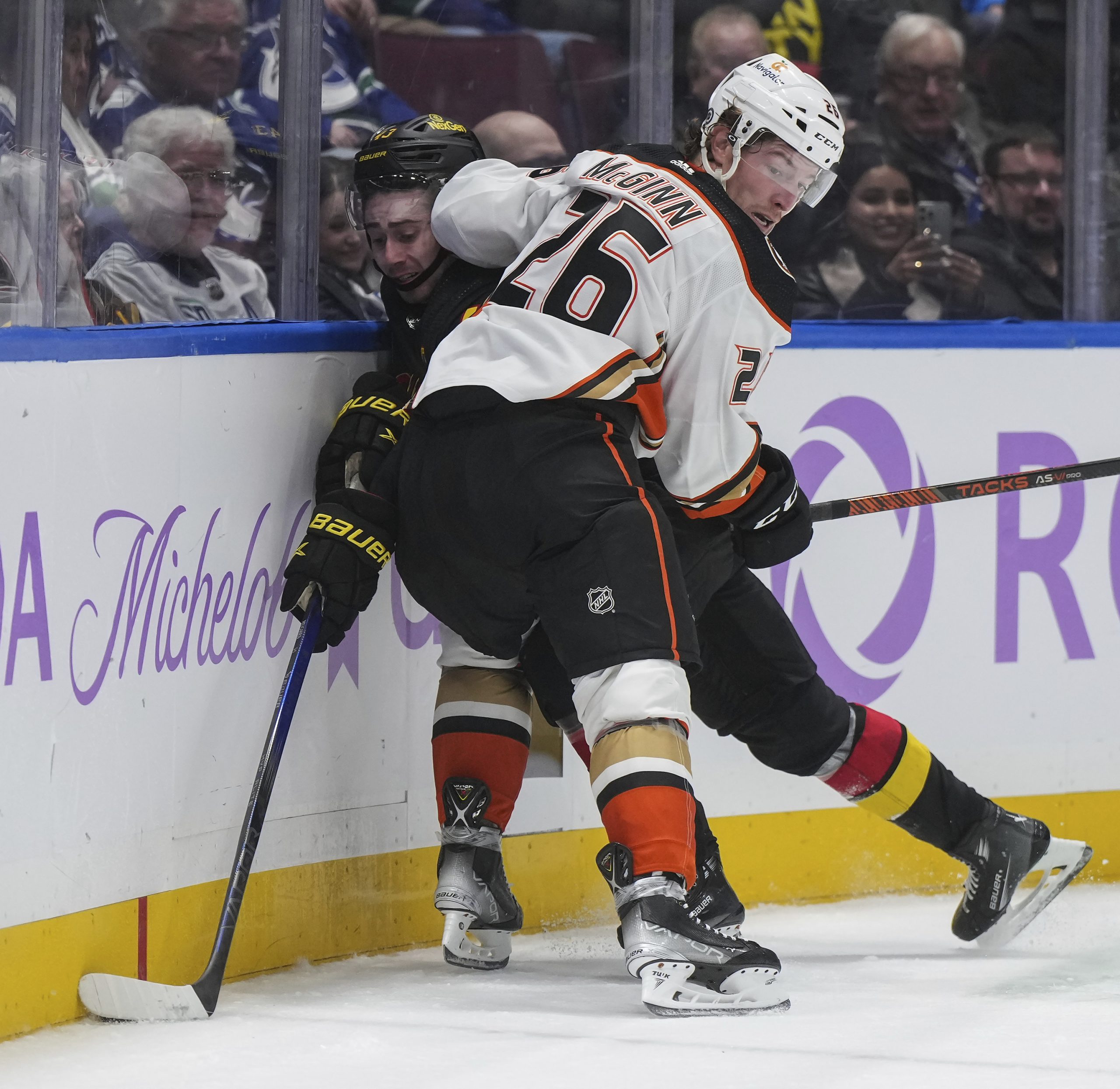 The Ducks’ Brock McGinn, right, checks the Vancouver Canucks’ Quinn...