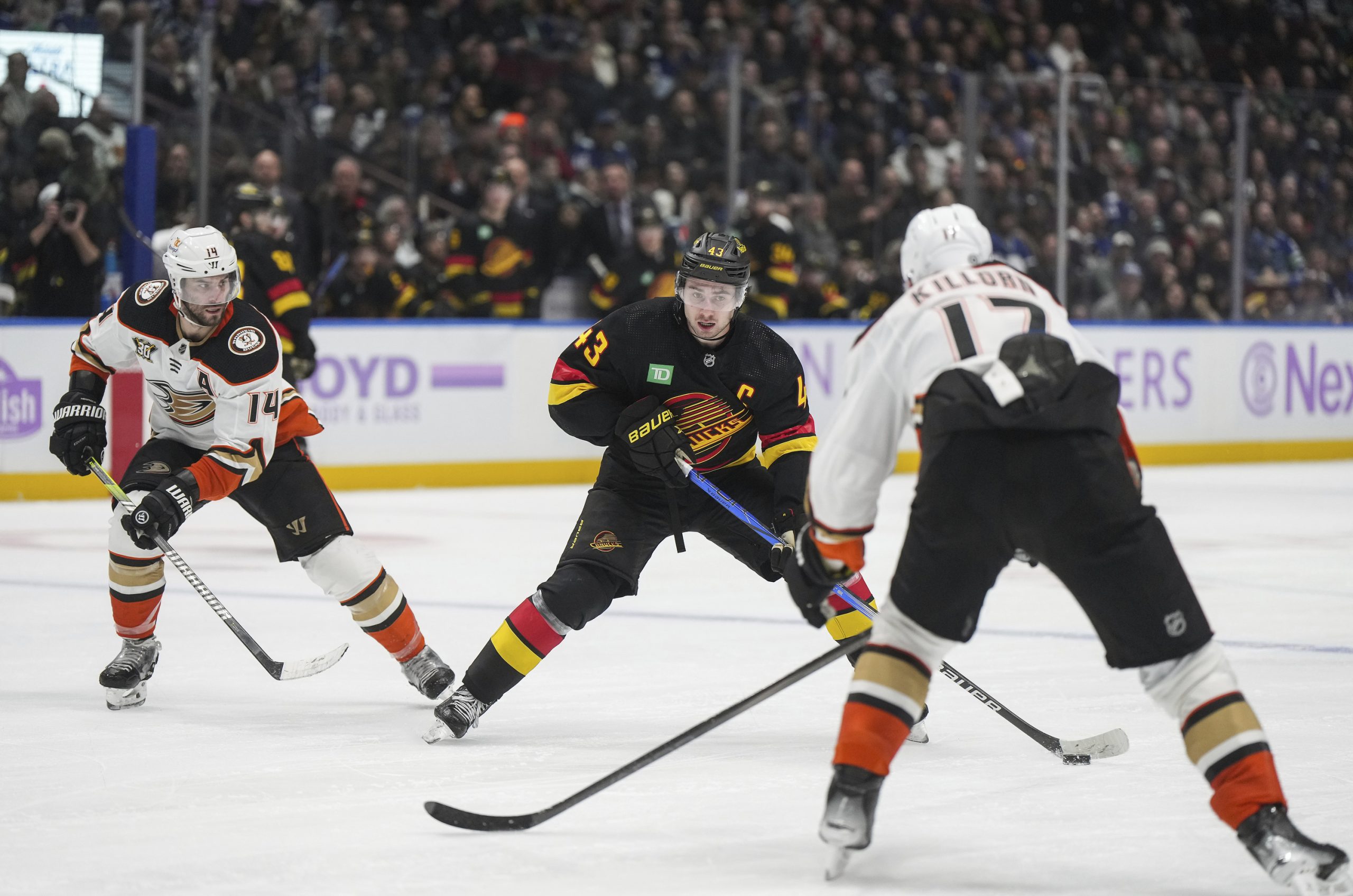 The Vancouver Canucks’ Quinn Hughes, center, skates with the puck...