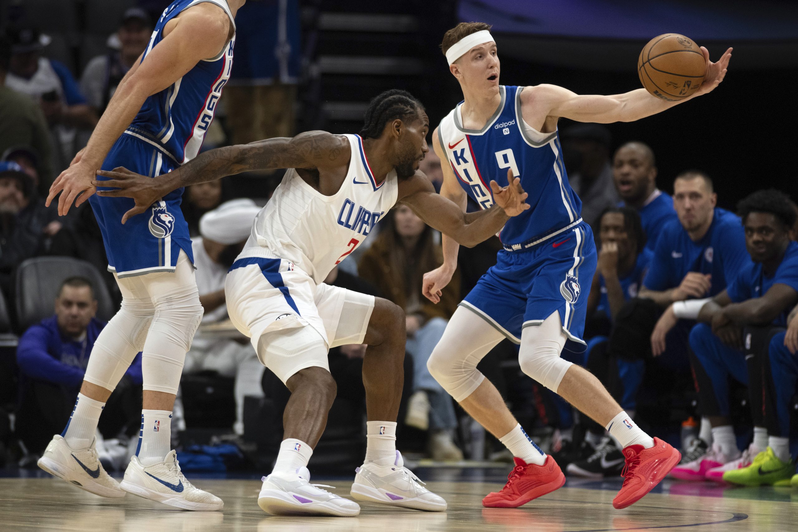 Clippers forward Kawhi Leonard, center, defends Sacramento Kings guard Kevin...