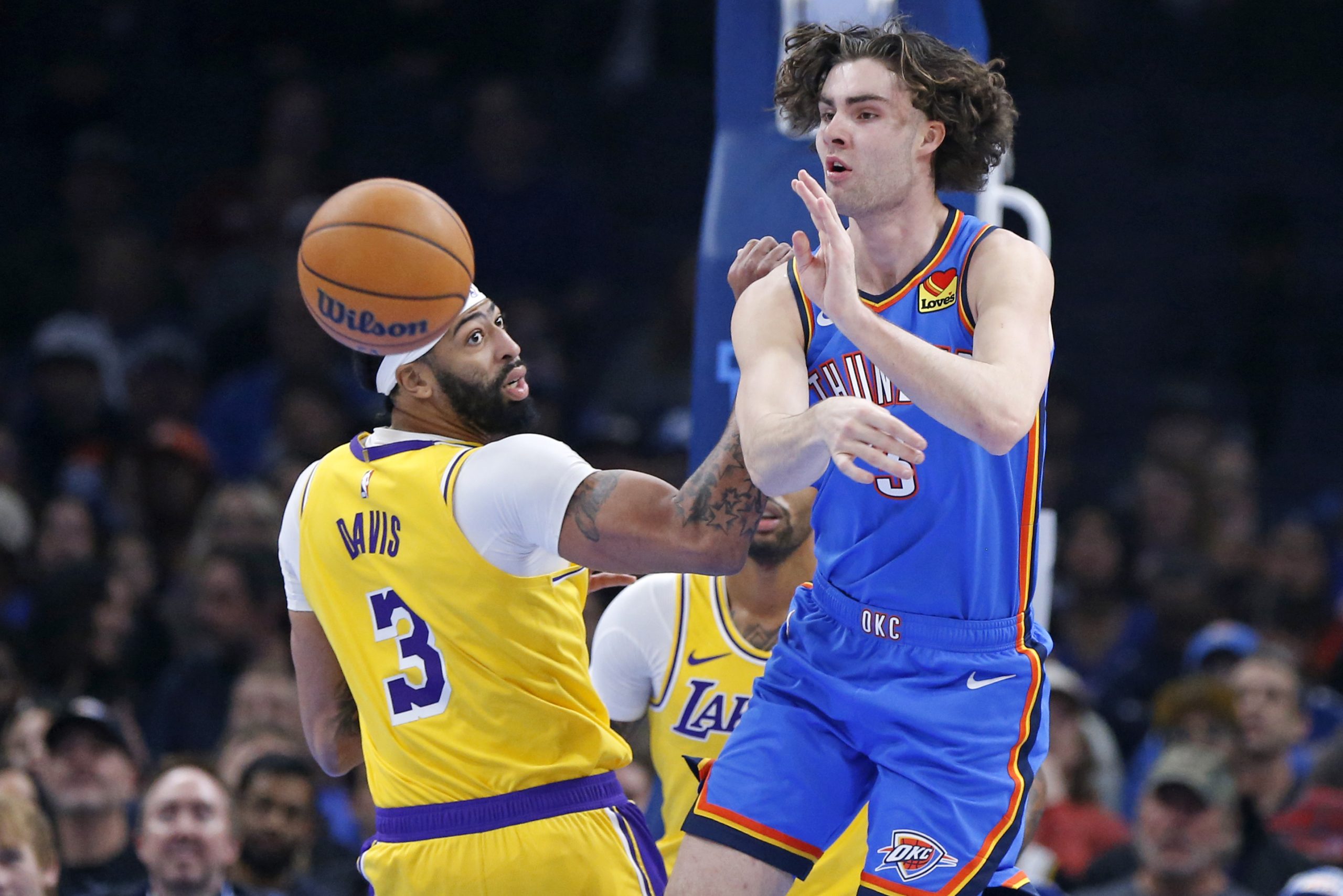 Oklahoma City Thunder guard Josh Giddey, right, passes the ball...