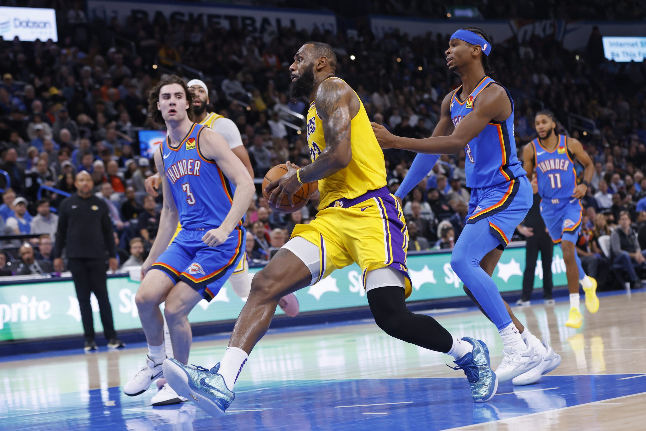 Lakers forward LeBron James, middle, drives to the basket as...