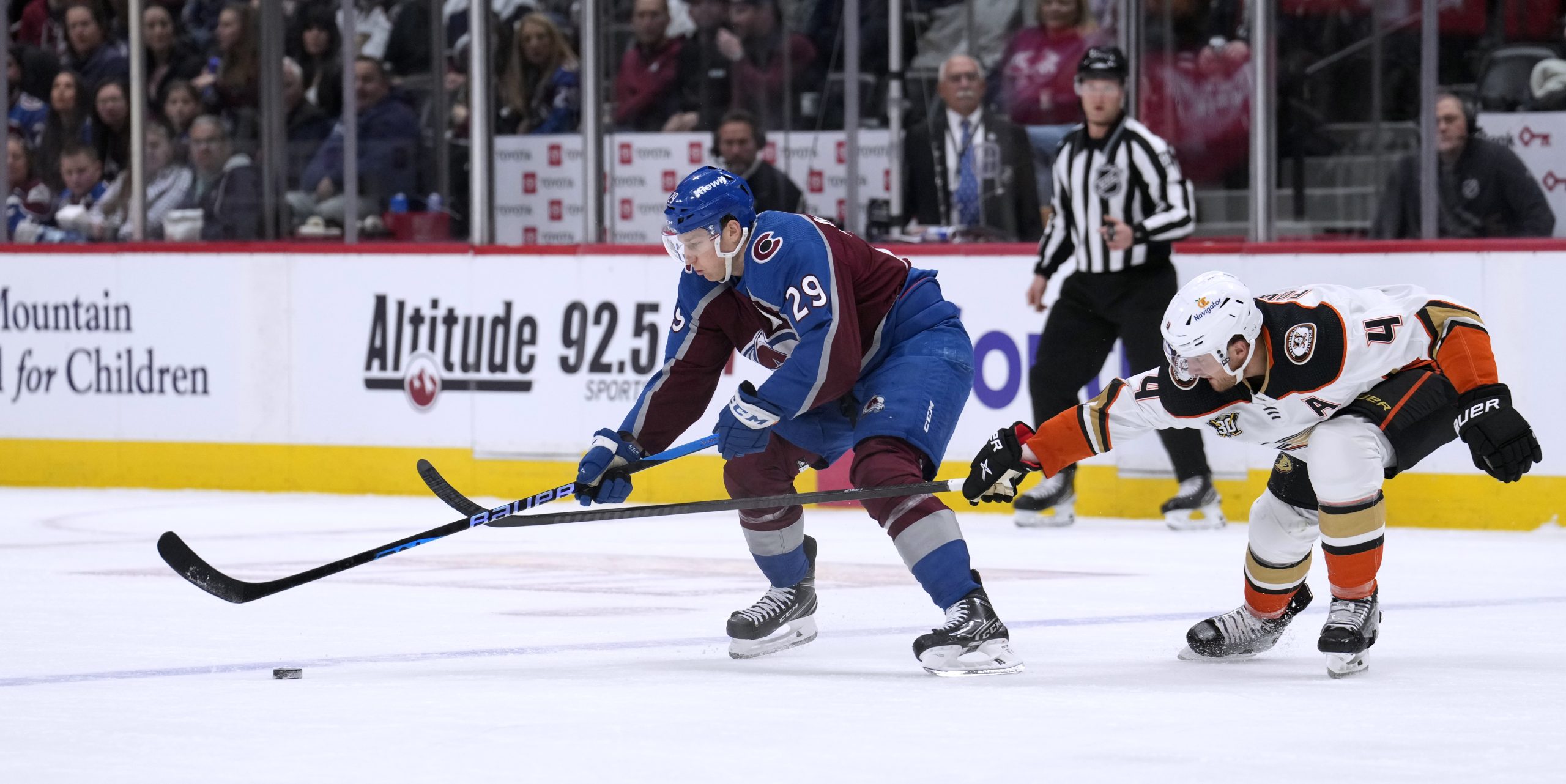 Colorado Avalanche center Nathan MacKinnon, left, reaches out to collect...