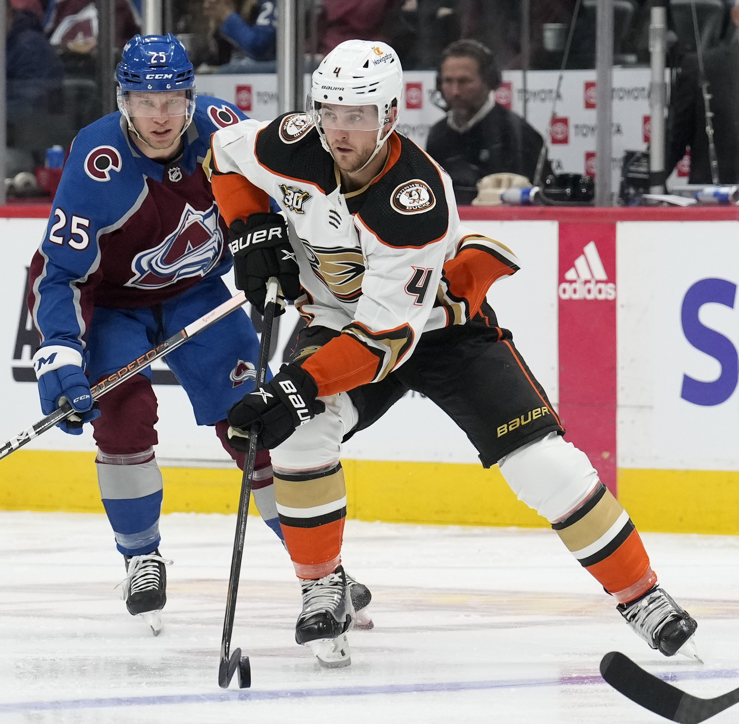 Ducks defenseman Cam Fowler, front, looks to pass the puck...