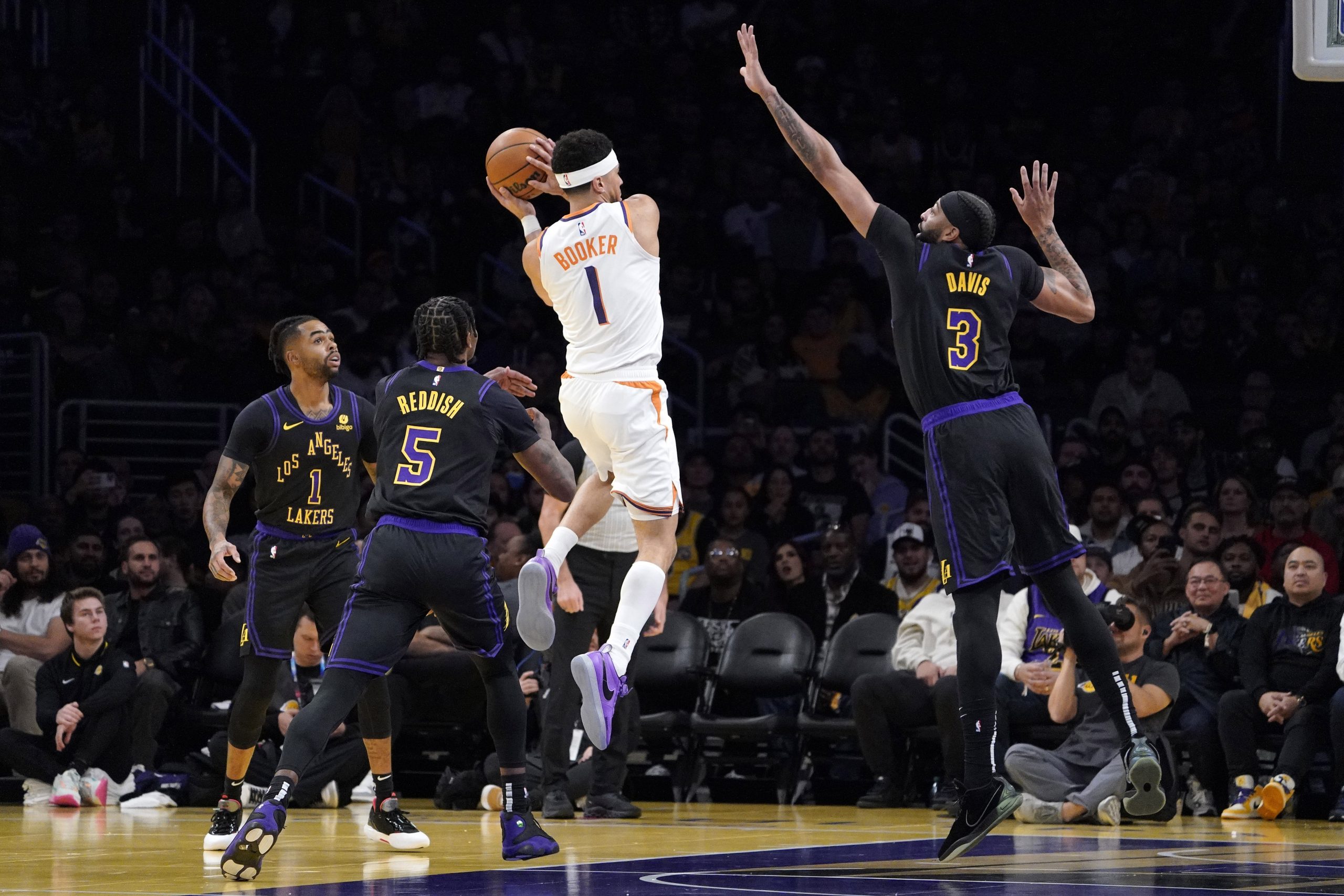Phoenix Suns guard Devin Booker, second from right, tries to...