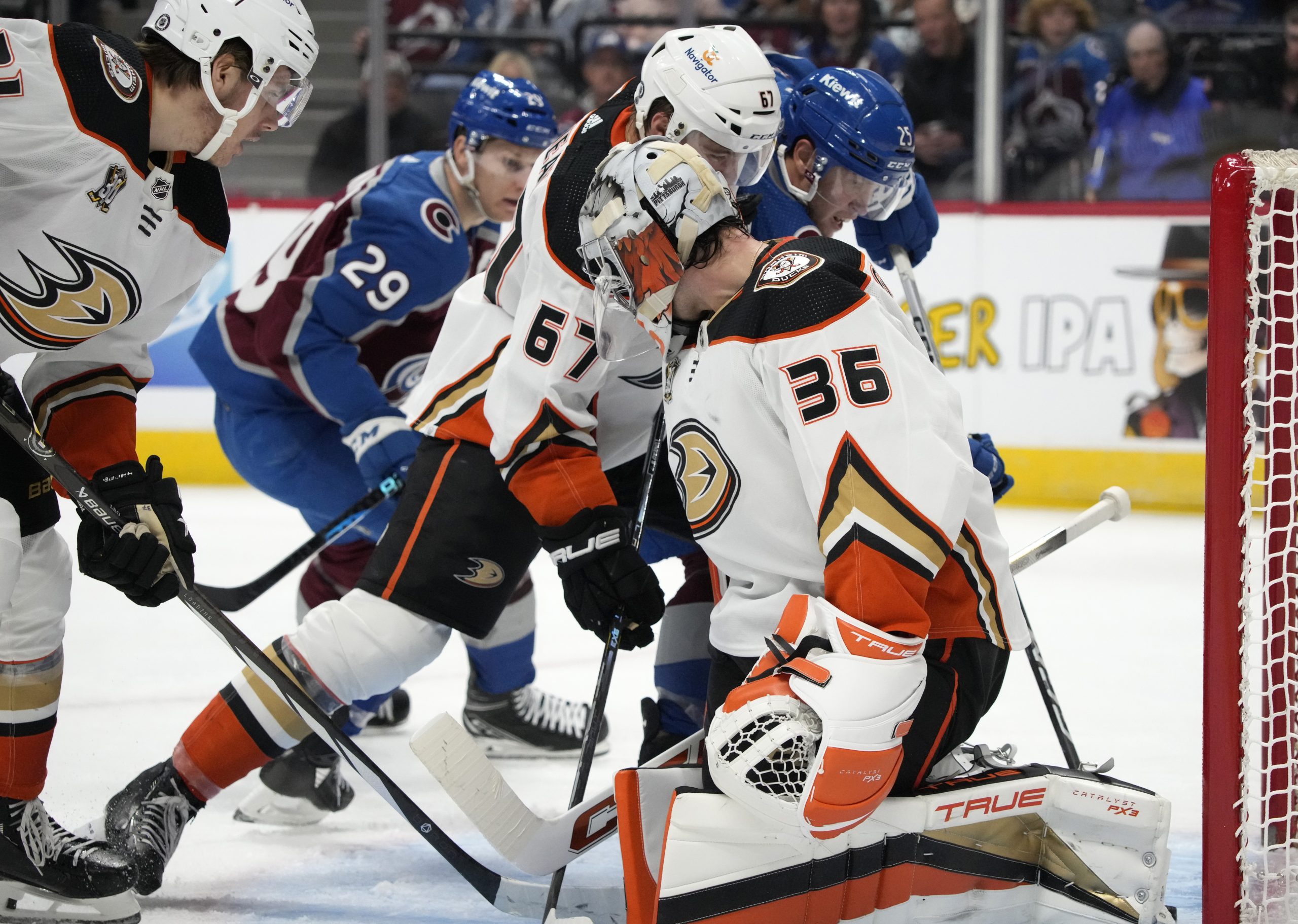 Ducks goaltender John Gibson, front, allows a shot by Colorado...