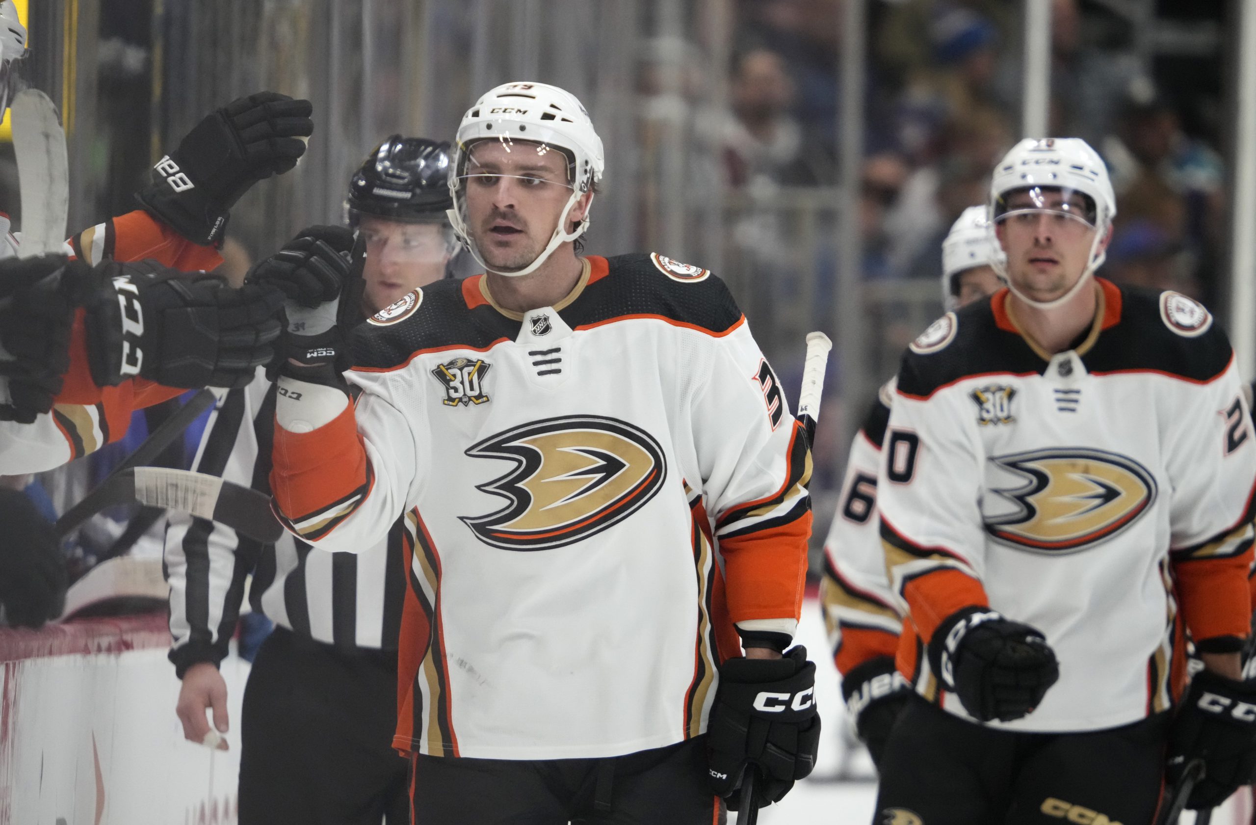 Ducks center Sam Carrick, right, is congratulated as he passes...