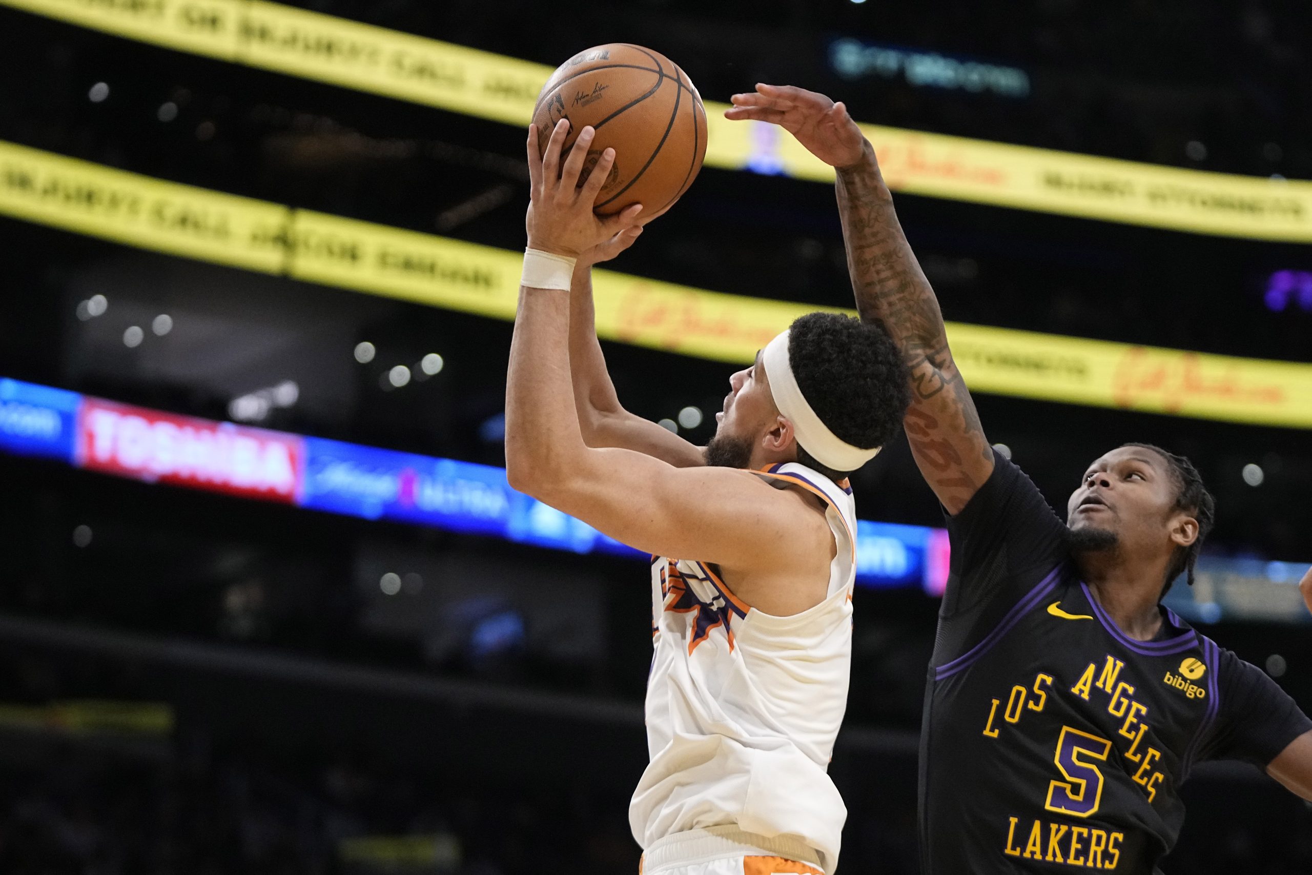 Phoenix Suns guard Devin Booker, left, shoots as Lakers forward...