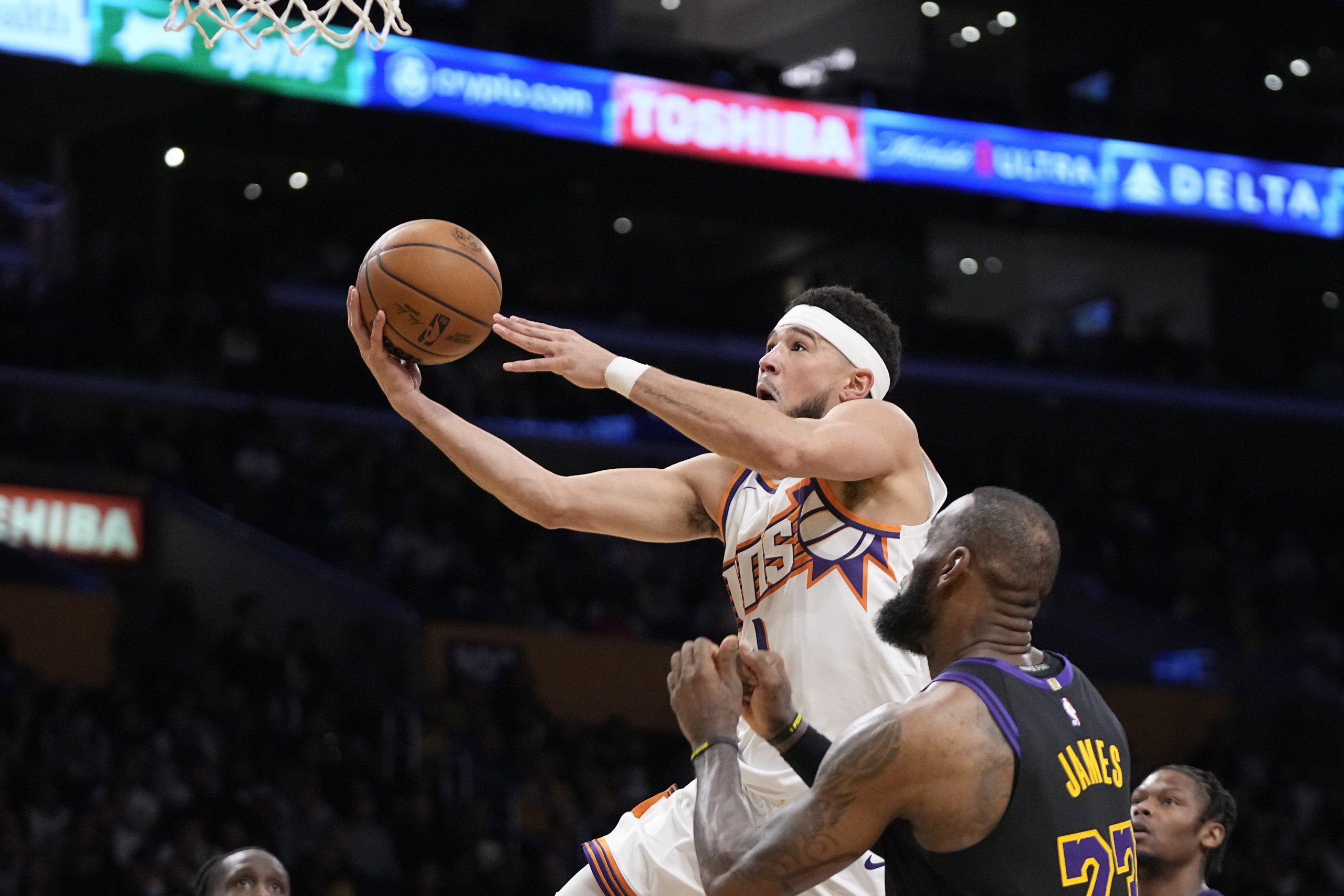 Phoenix Suns guard Devin Booker, left, shoots as Lakers forward...