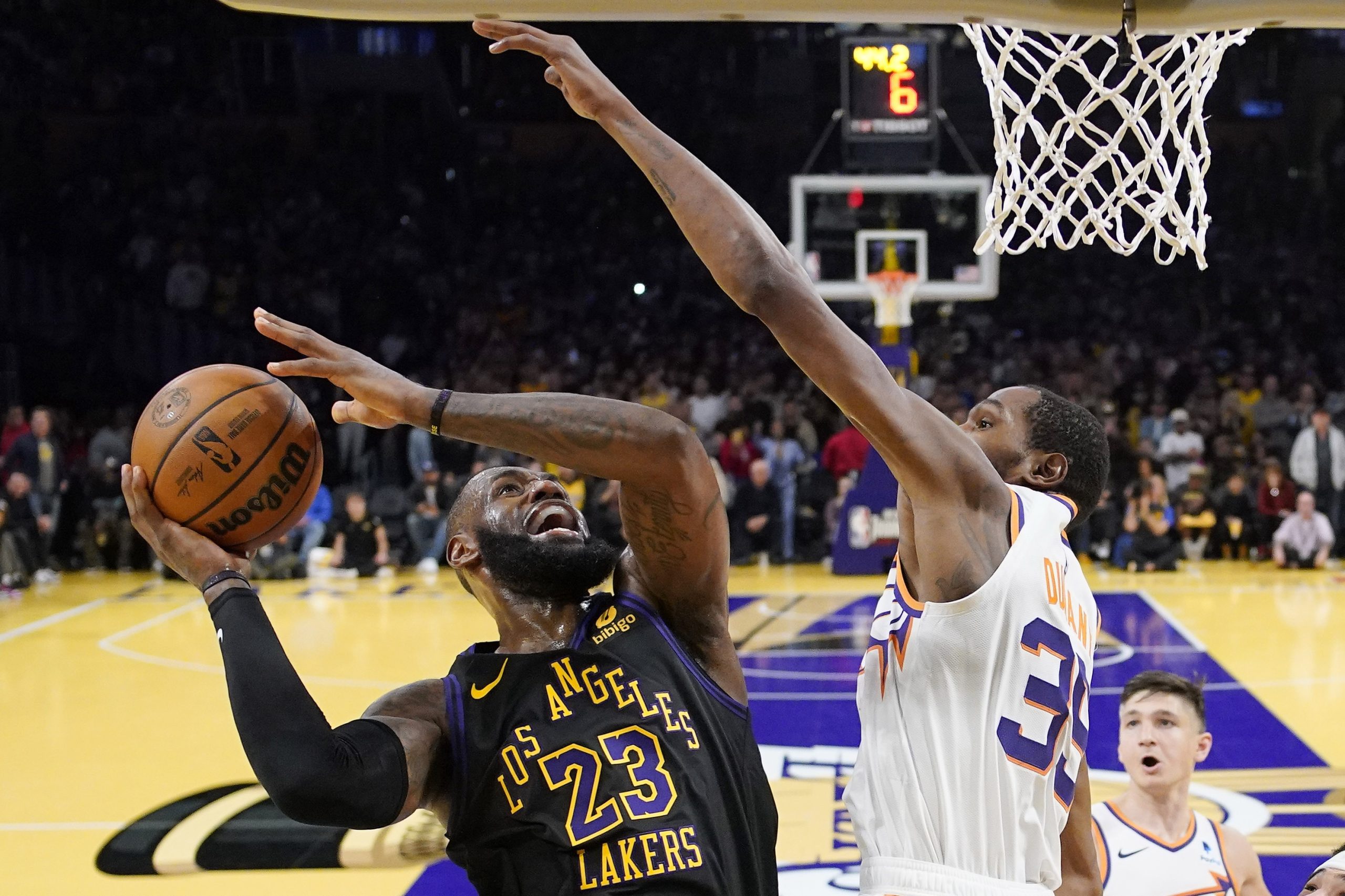 Lakers forward LeBron James, left, shoots as Phoenix Suns forward...