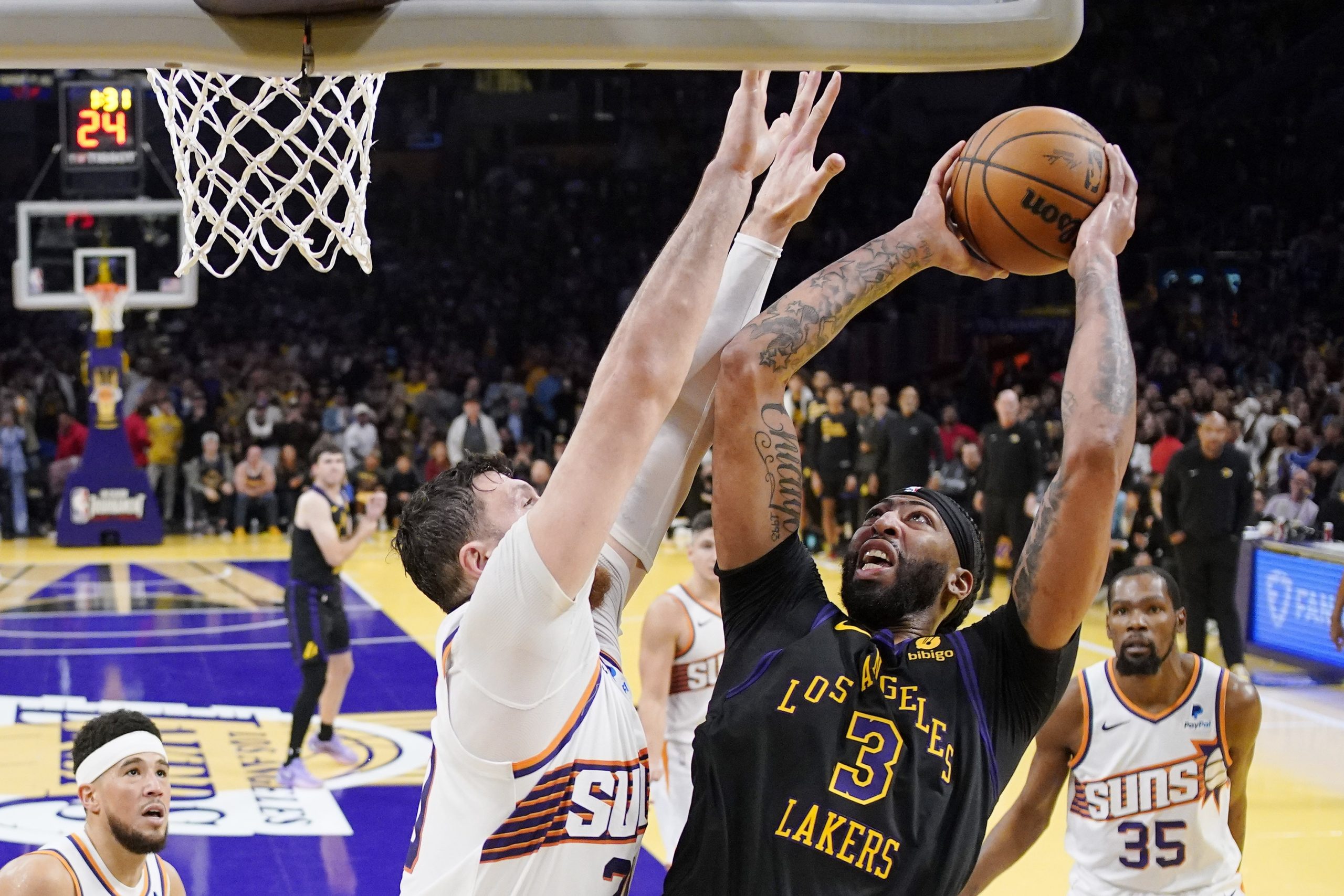 Lakers forward Anthony Davis, right, shoots as Phoenix Suns center...