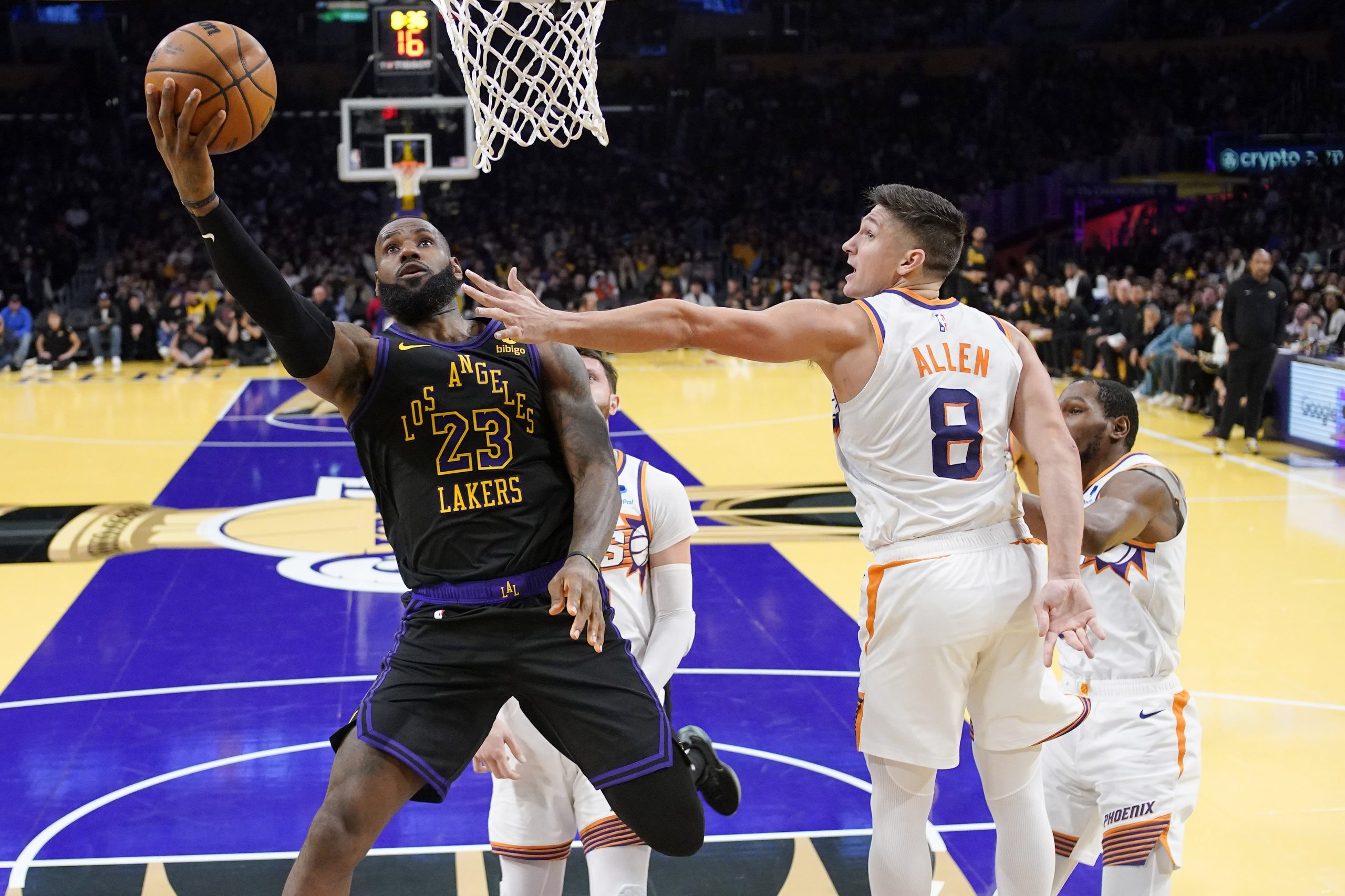 Lakers forward LeBron James, left, shoots as Phoenix Suns guard...