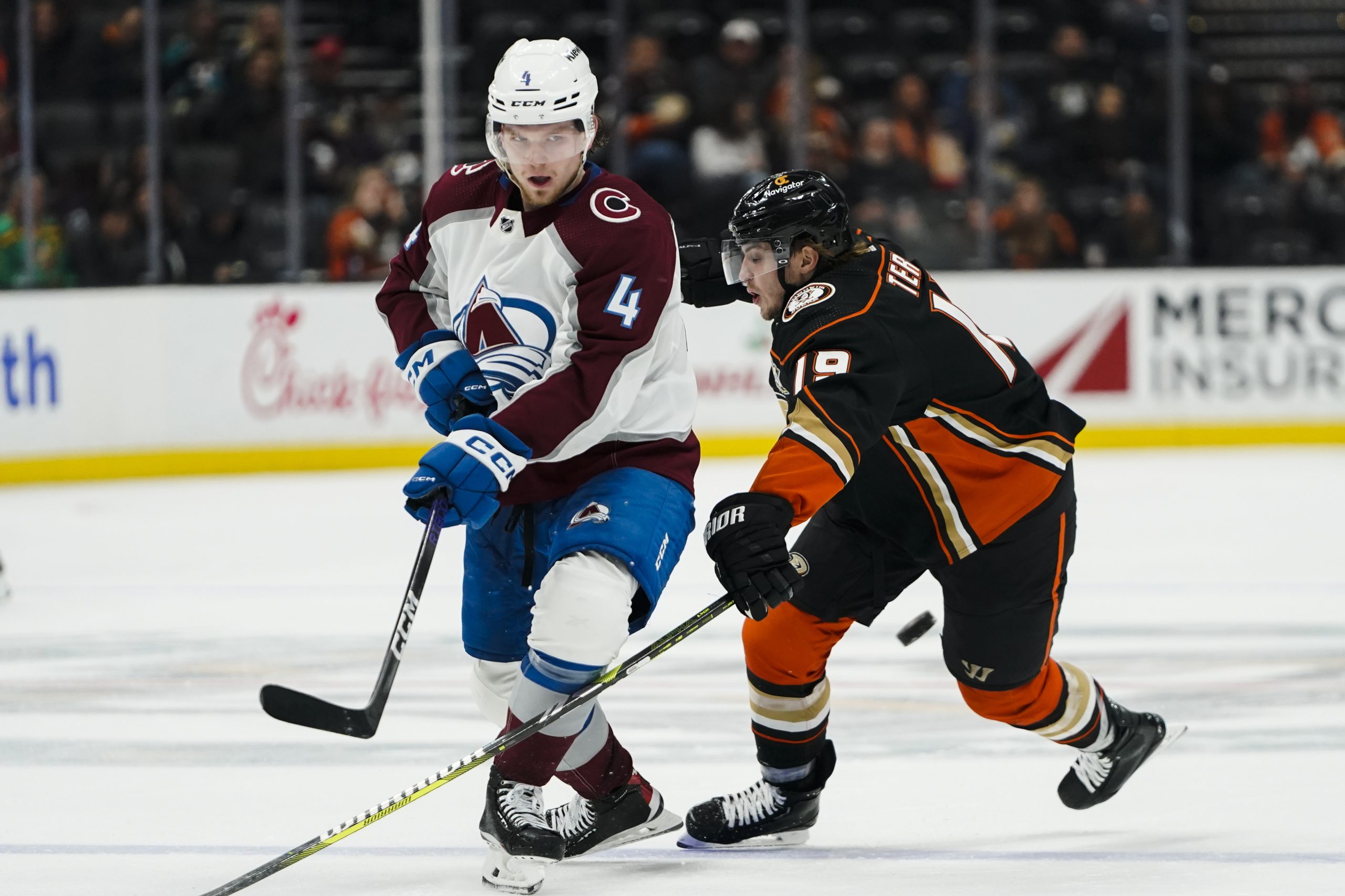 Colorado Avalanche defenseman Bowen Byram, left, hits the puck past...