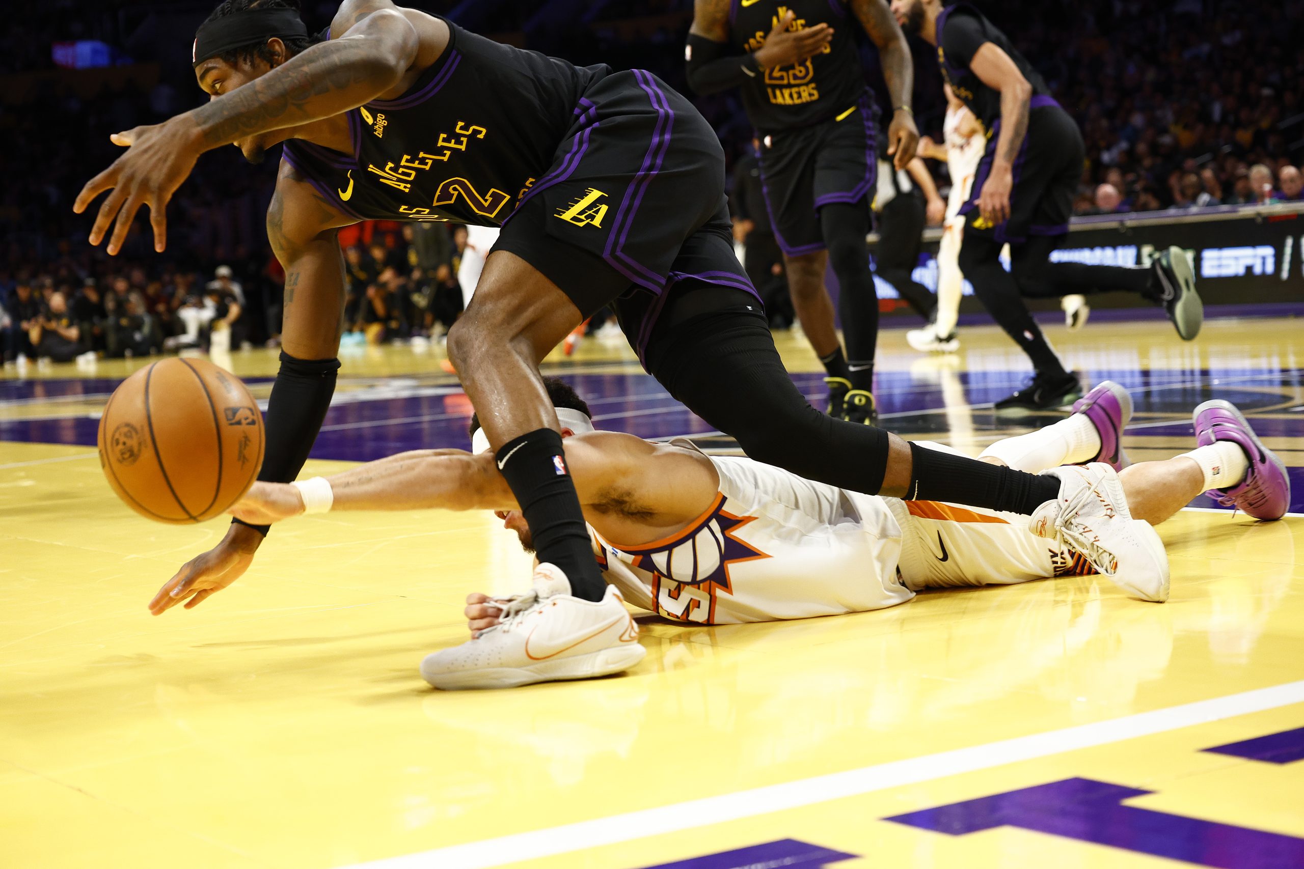 Lakers forward Jarred Vanderbilt, left, scoops up a loose ball...