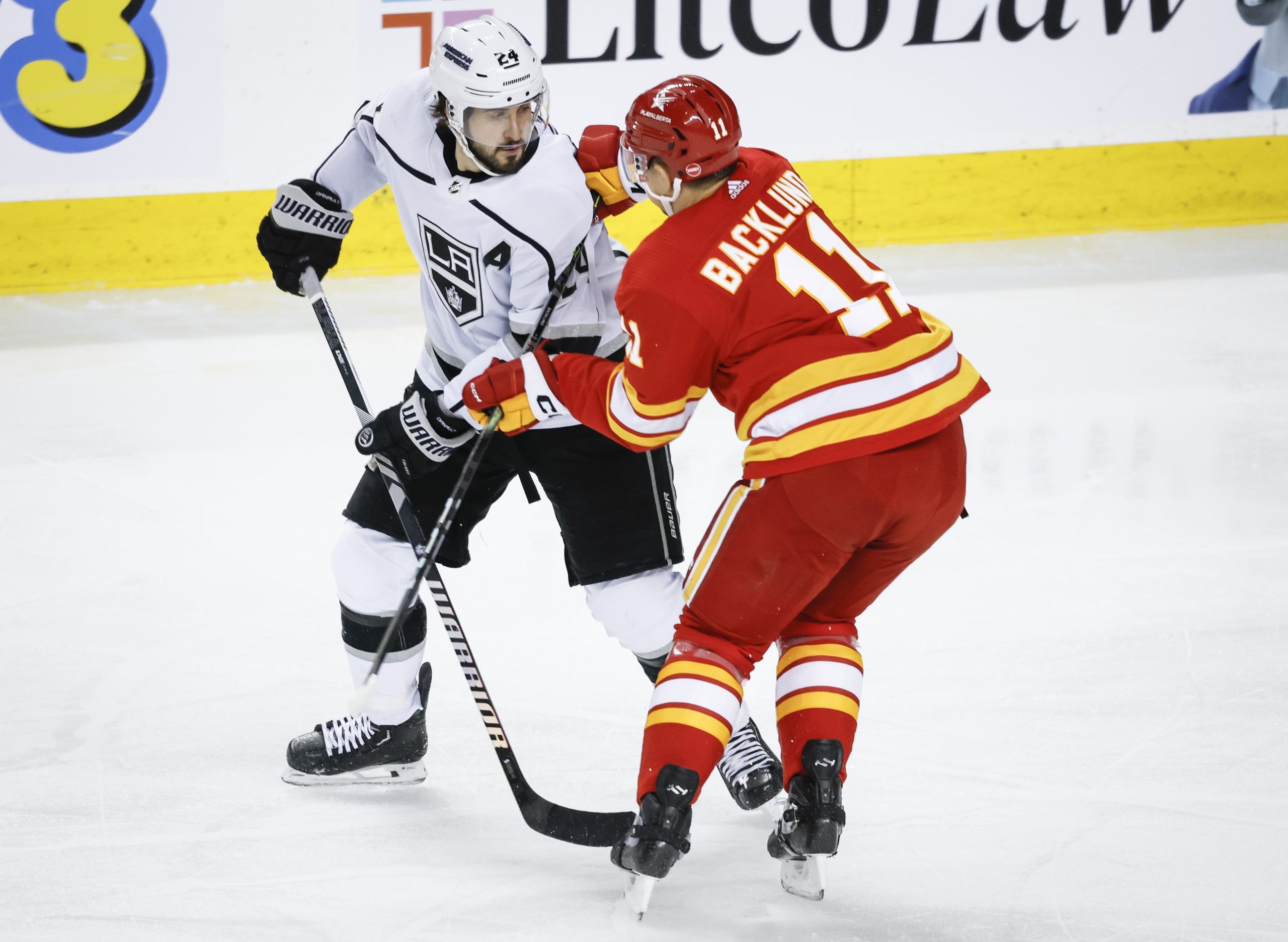 Kings forward Phillip Danault, left, is checked by Calgary Flames...