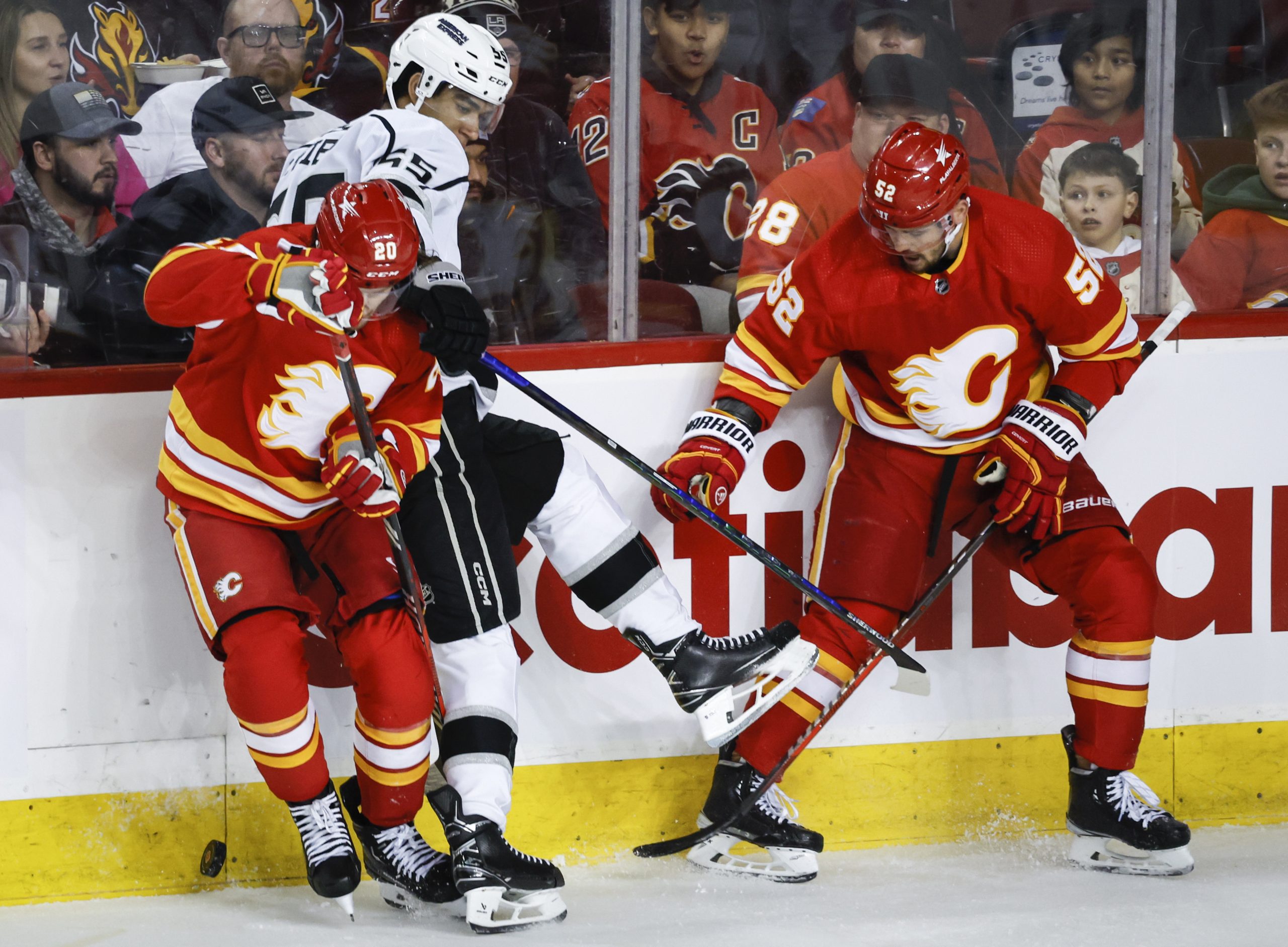 Kings forward Quinton Byfield, center, is checked by Calgary Flames...