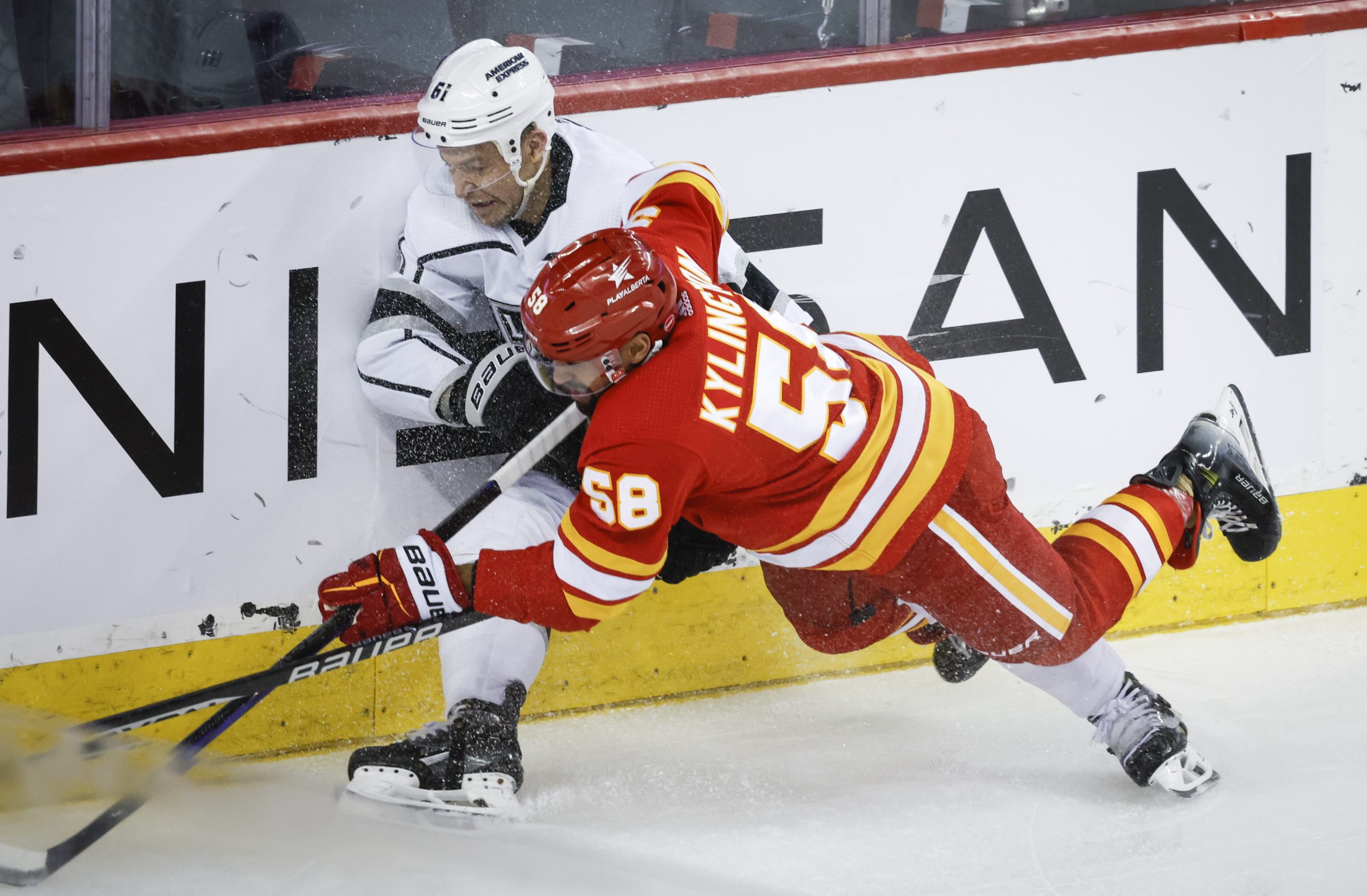 Kings forward Trevor Lewis, left, is checked by Calgary Flames...