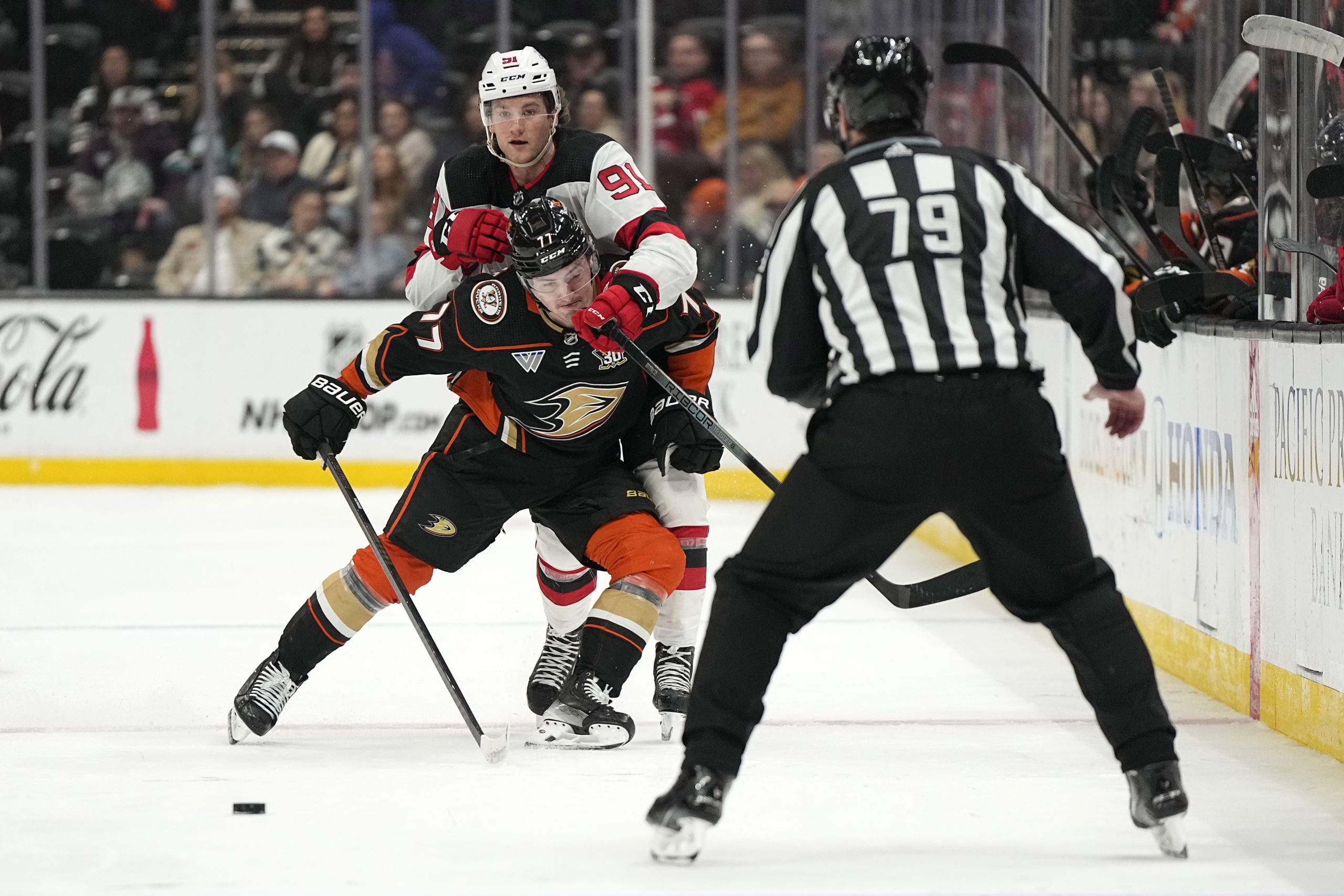 Ducks right wing Frank Vatrano, center, checks New Jersey Devils...