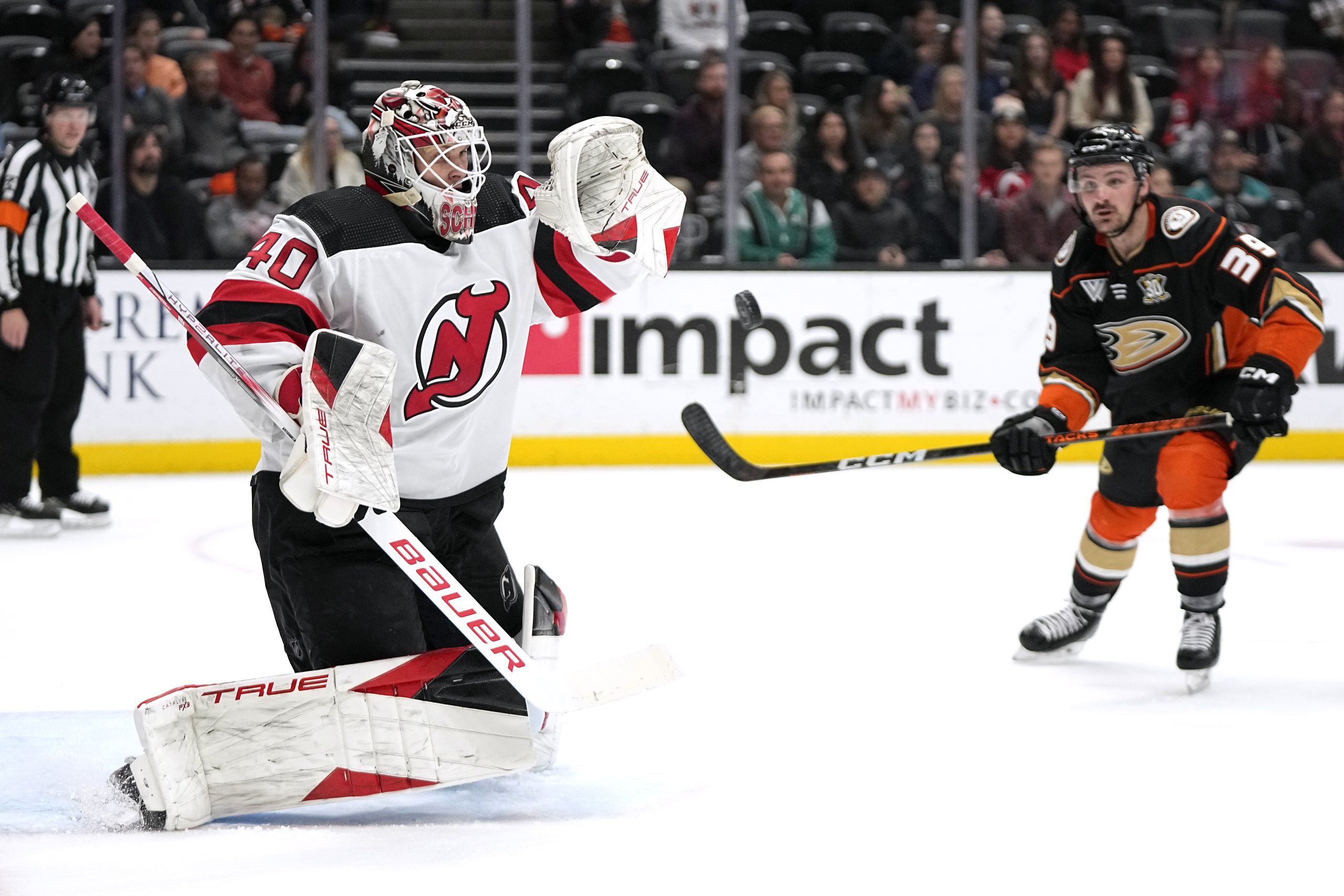 New Jersey Devils goaltender Akira Schmid, left, stops a shot...