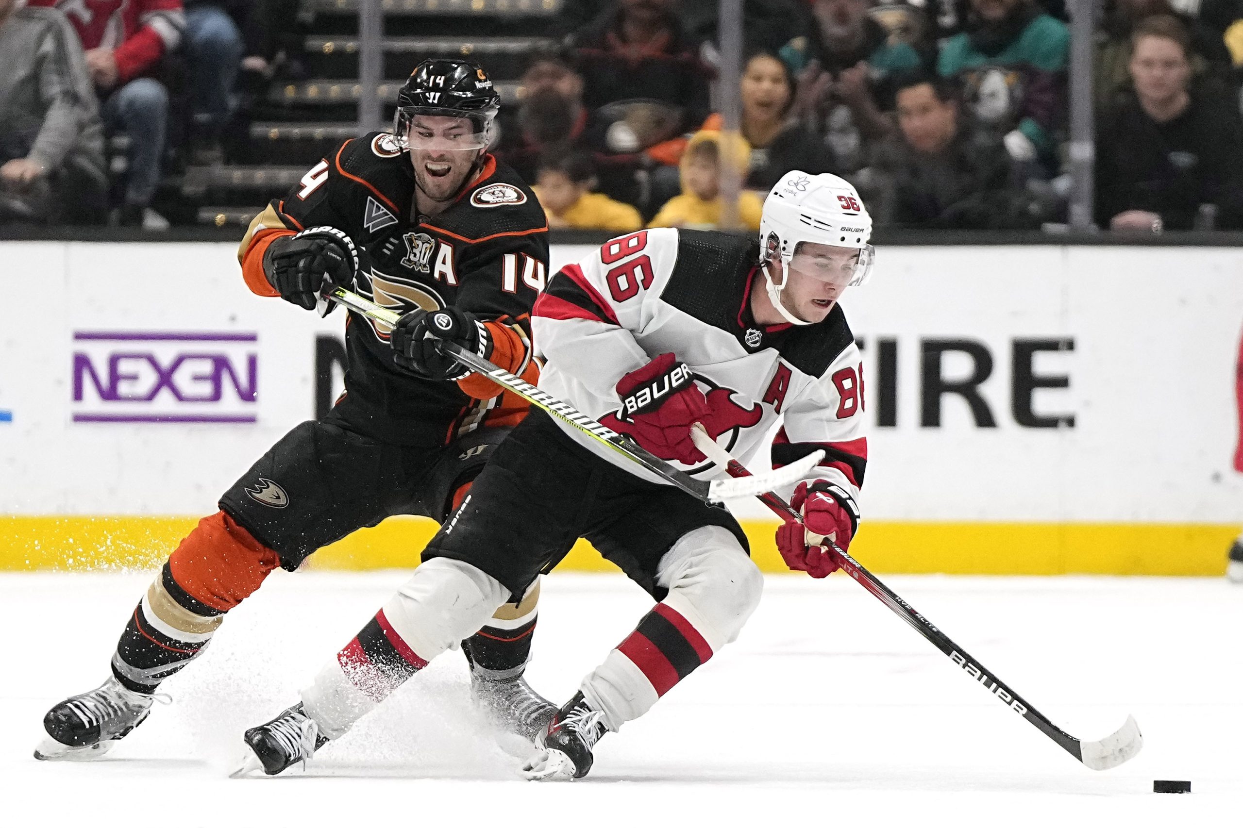 Ducks center Adam Henrique, left, reaches in on New Jersey...