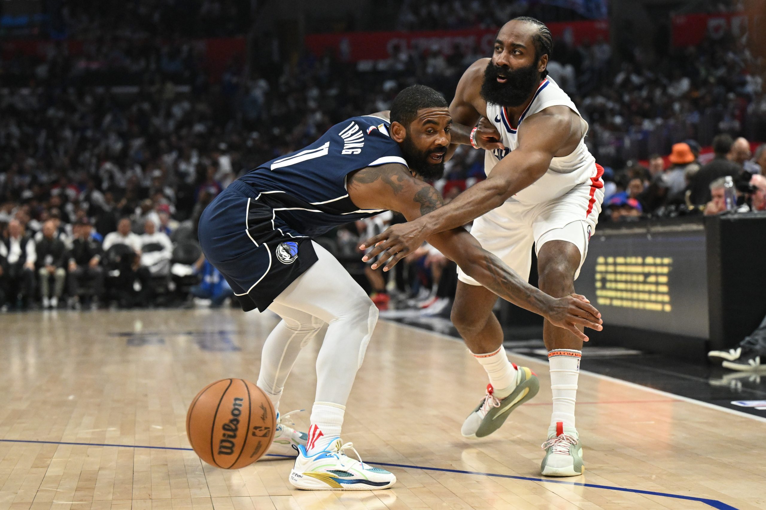 Clippers guard James Harden, right, passes the ball past Dallas...