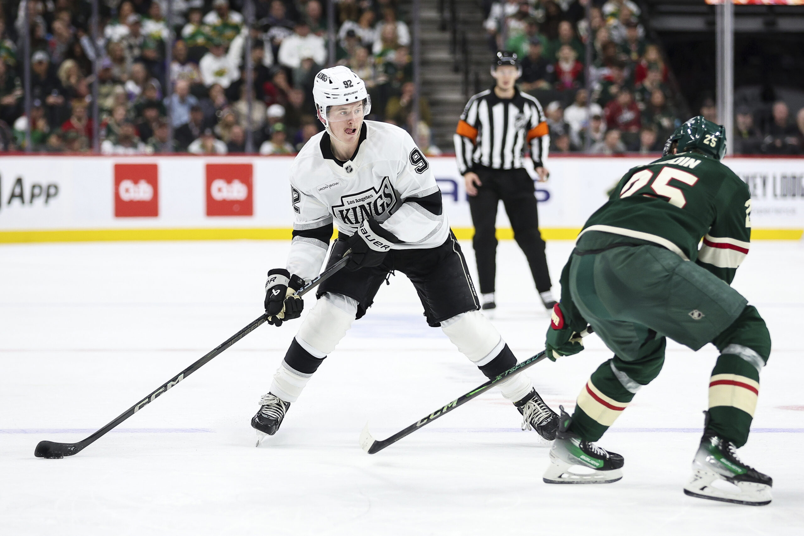 Kings defenseman Brandt Clarke, left, skates with the puck as...