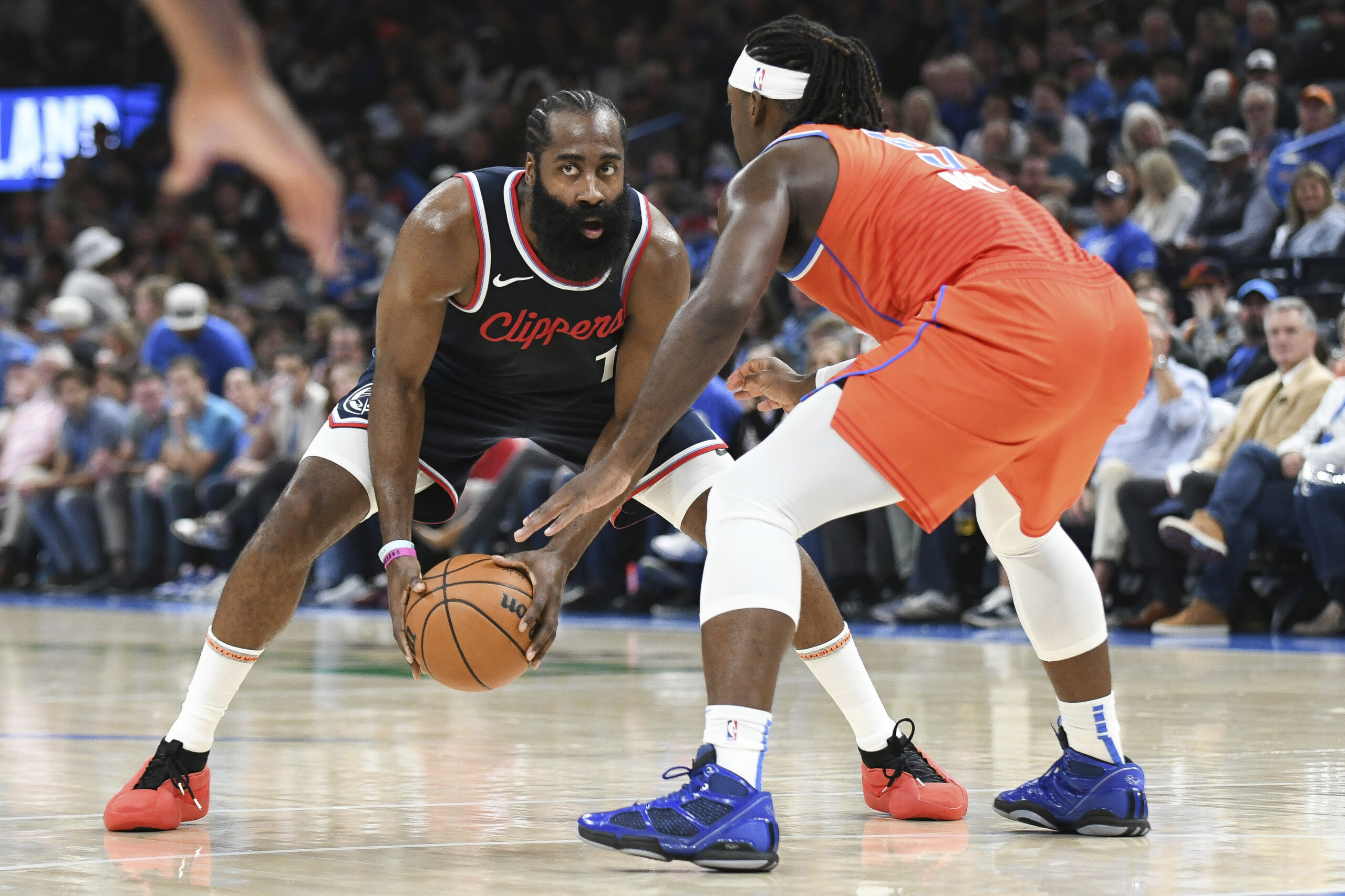 Clippers guard James Harden, left, looks for an opening past...