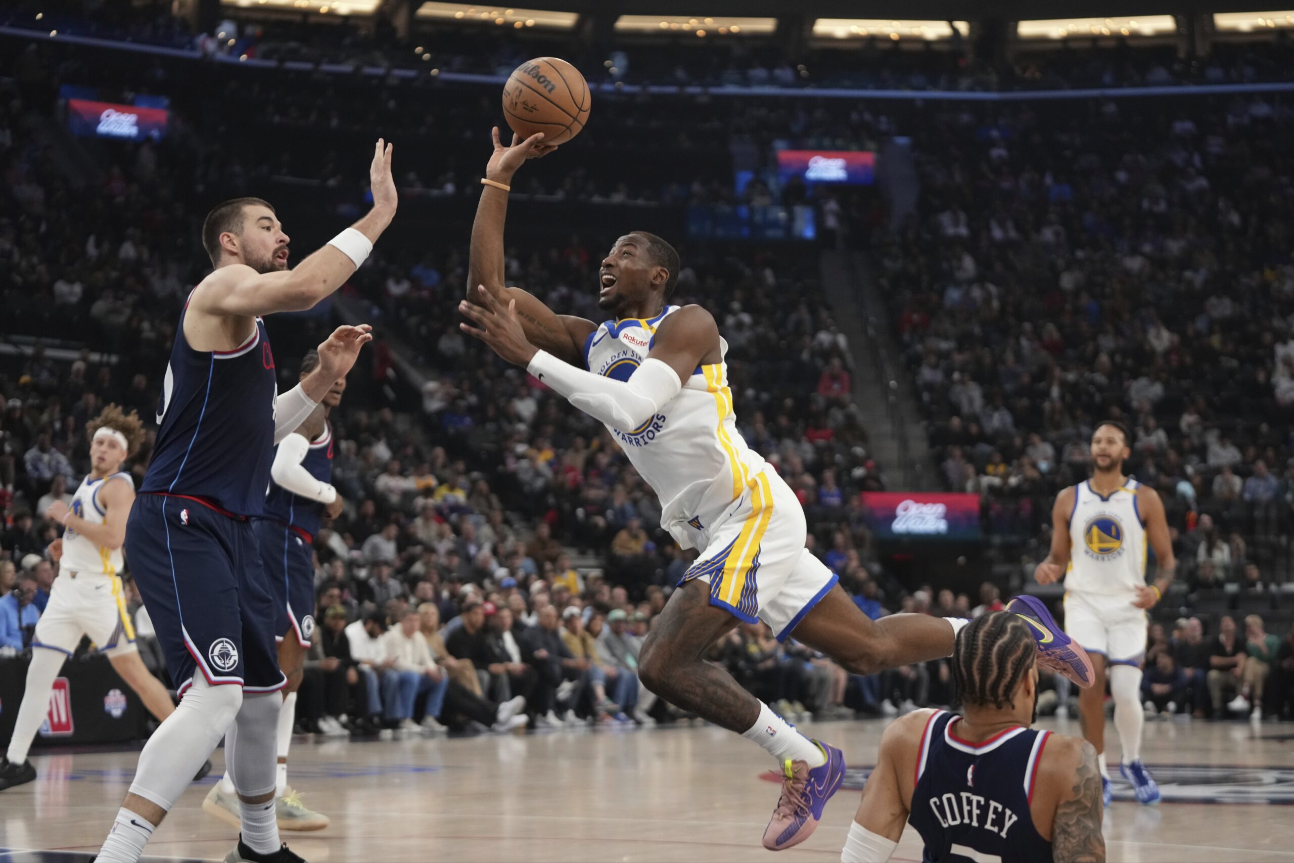 Golden State Warriors forward Jonathan Kuminga, center, shoots as Clippers...