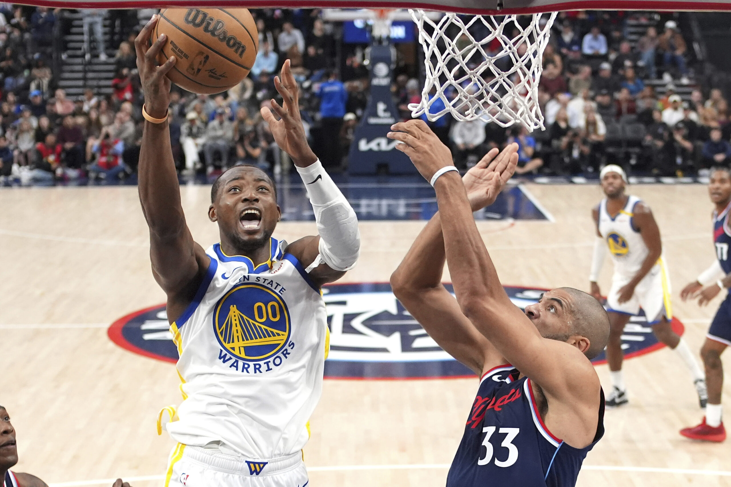 Golden State Warriors forward Jonathan Kuminga, left, shoots as Clippers...