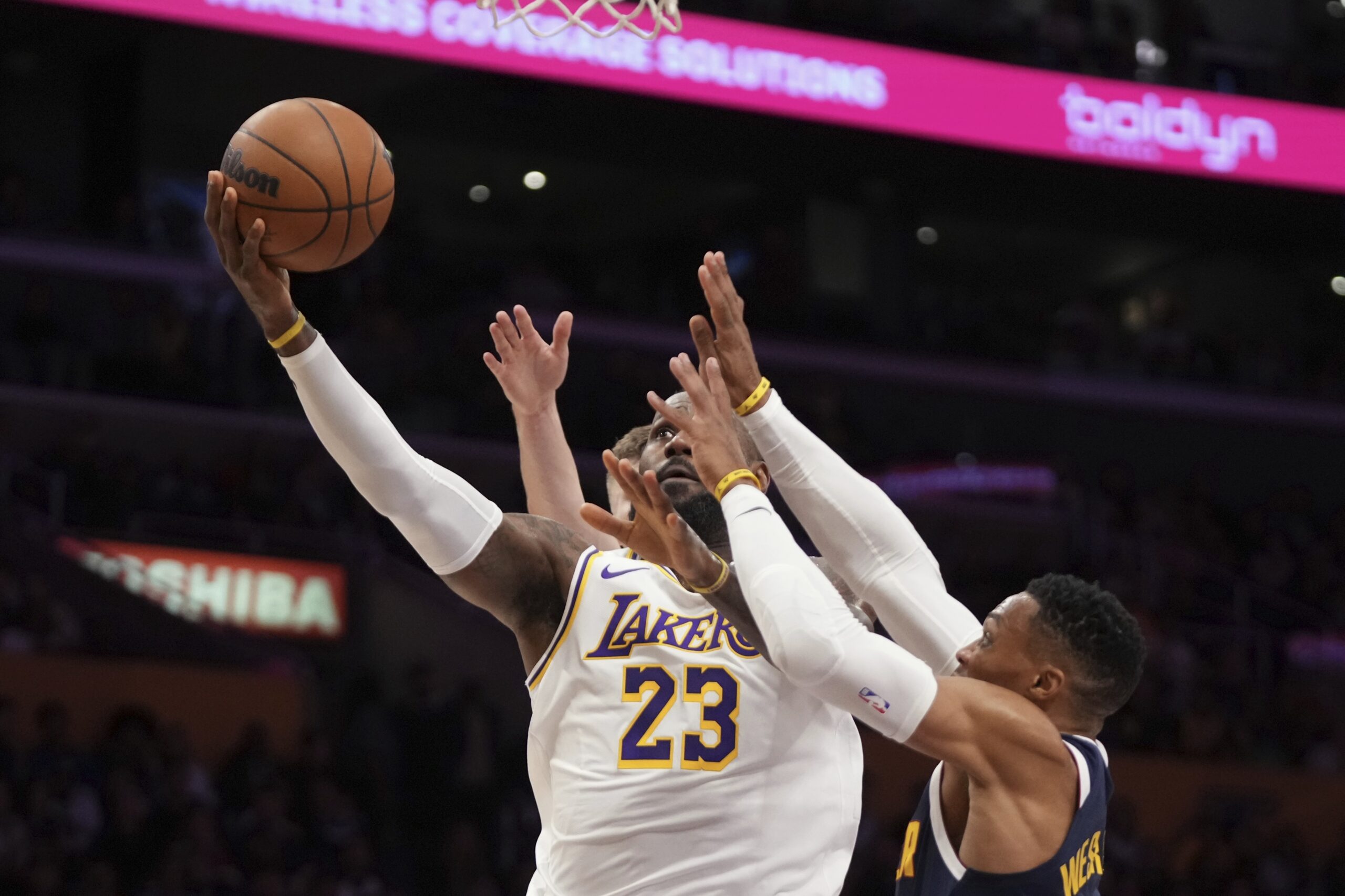 Lakers forward LeBron James, left, shoots as Denver Nuggets guard...