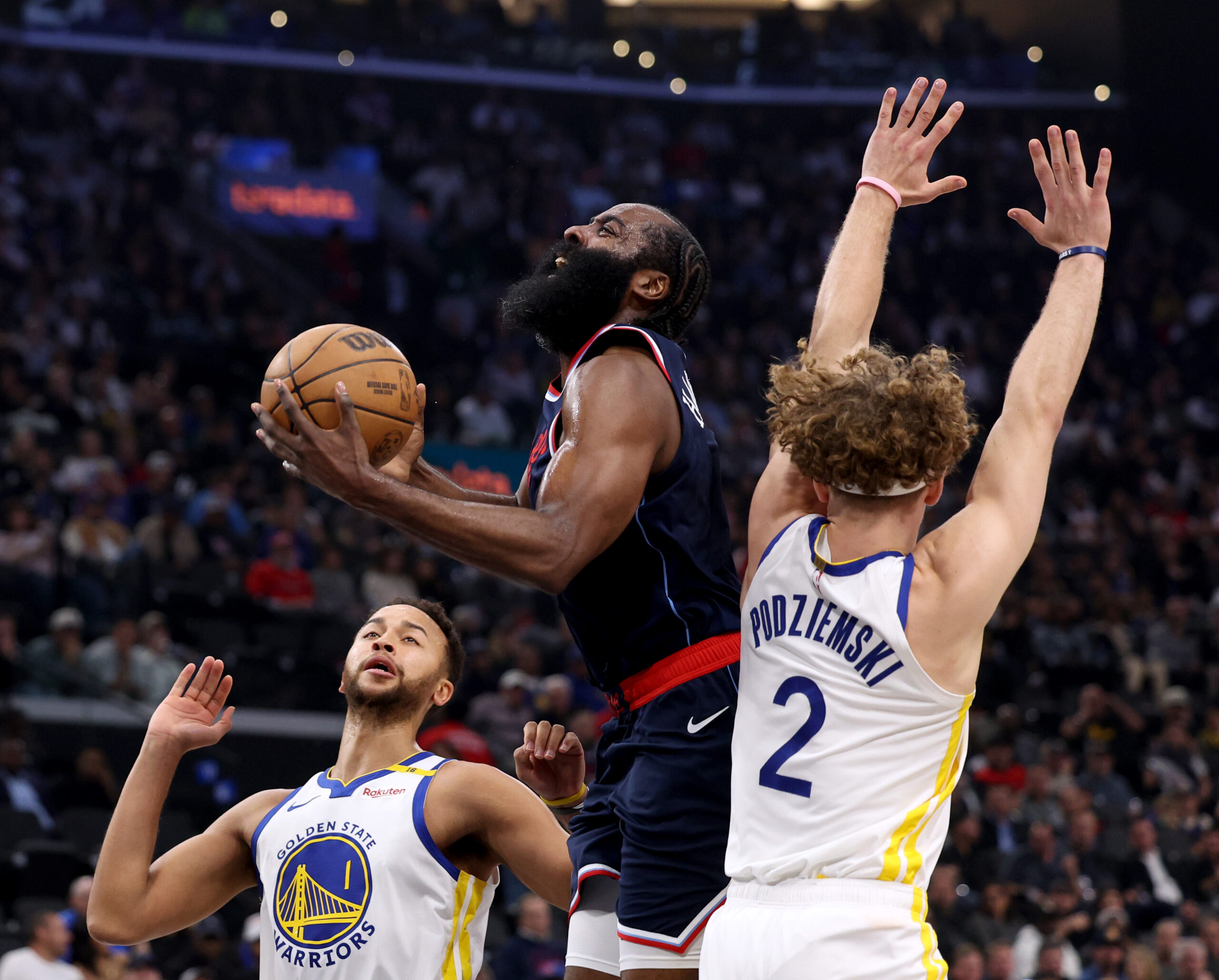 Clippers guard James Harden, left, reacts as he drives to...