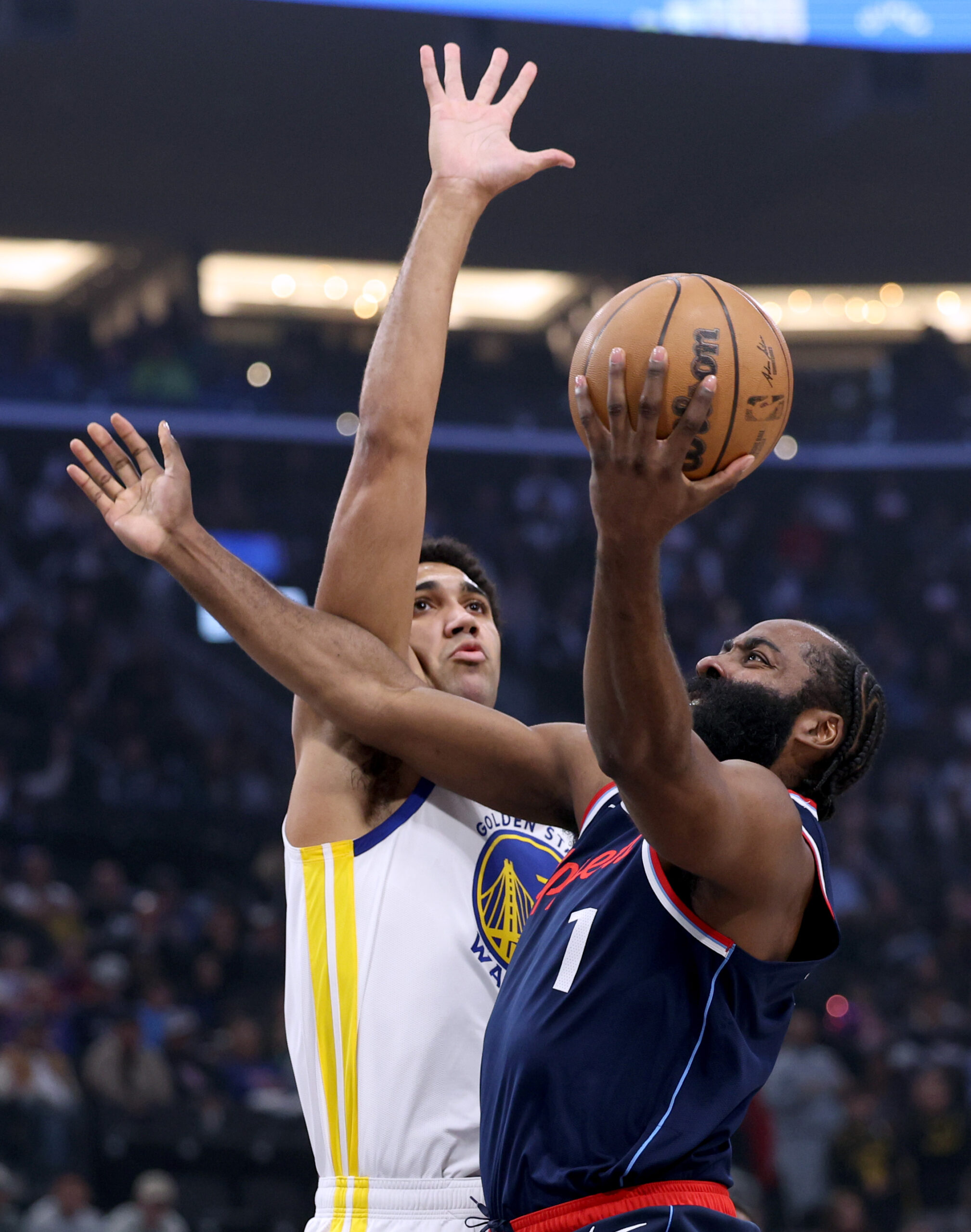 Clippers guard James Harden scores on a layup in front...