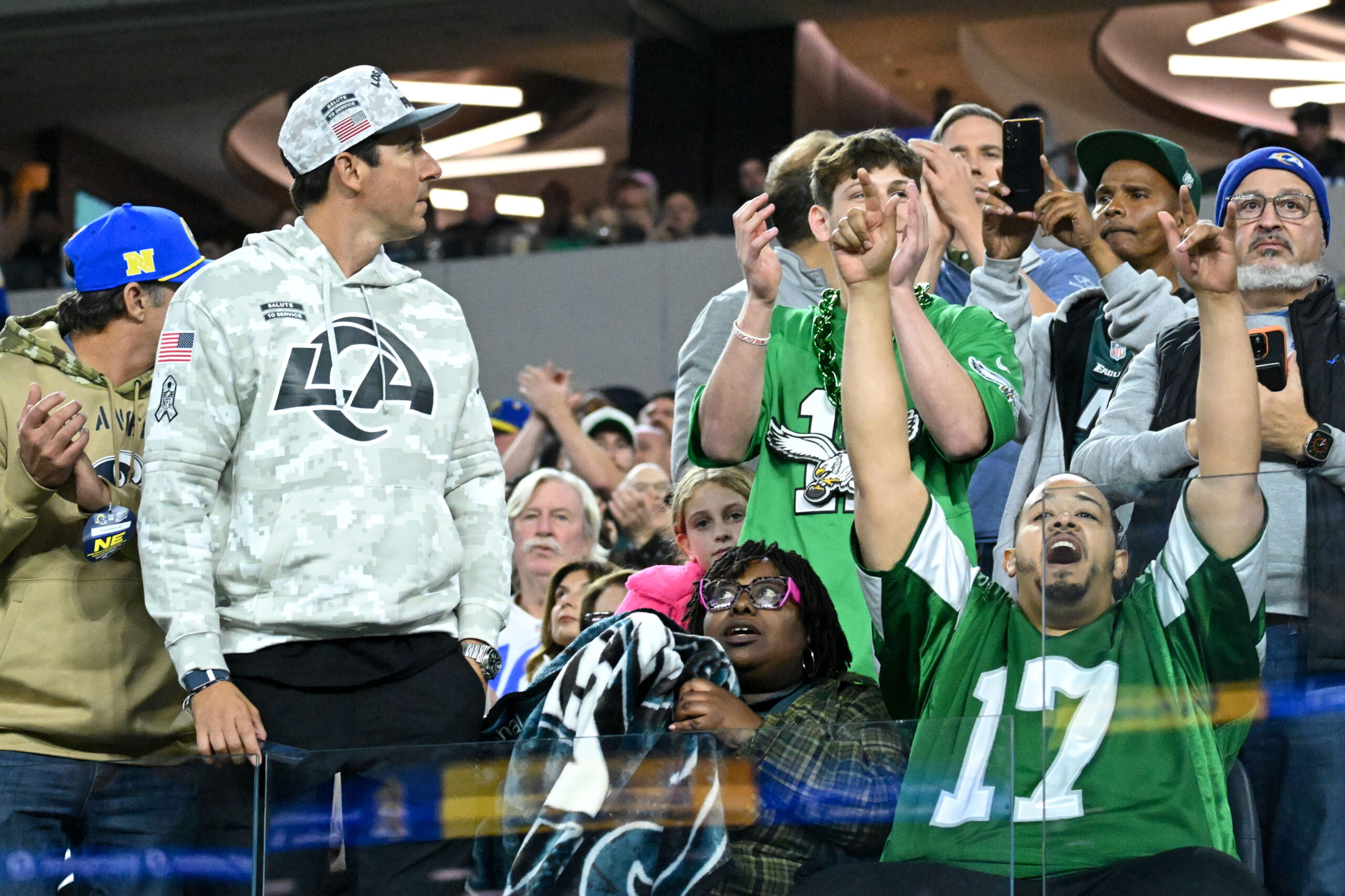 Eagles fans cheer as a Rams fan looks on at...