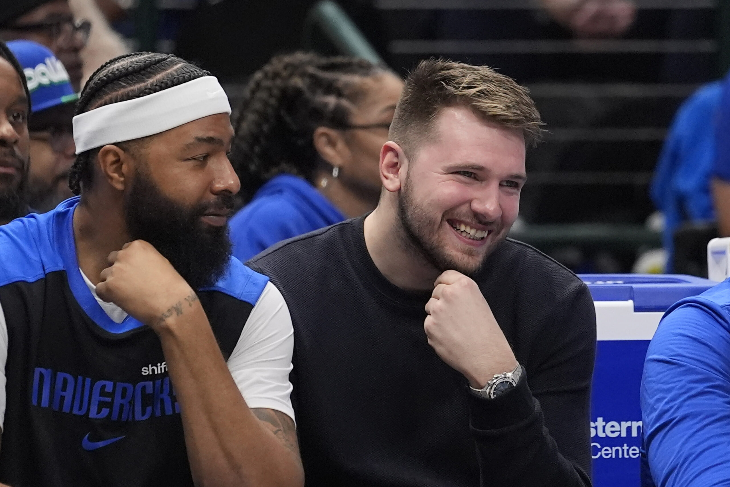 Dallas Mavericks guard Luka Doncic, right smiles while watching from...