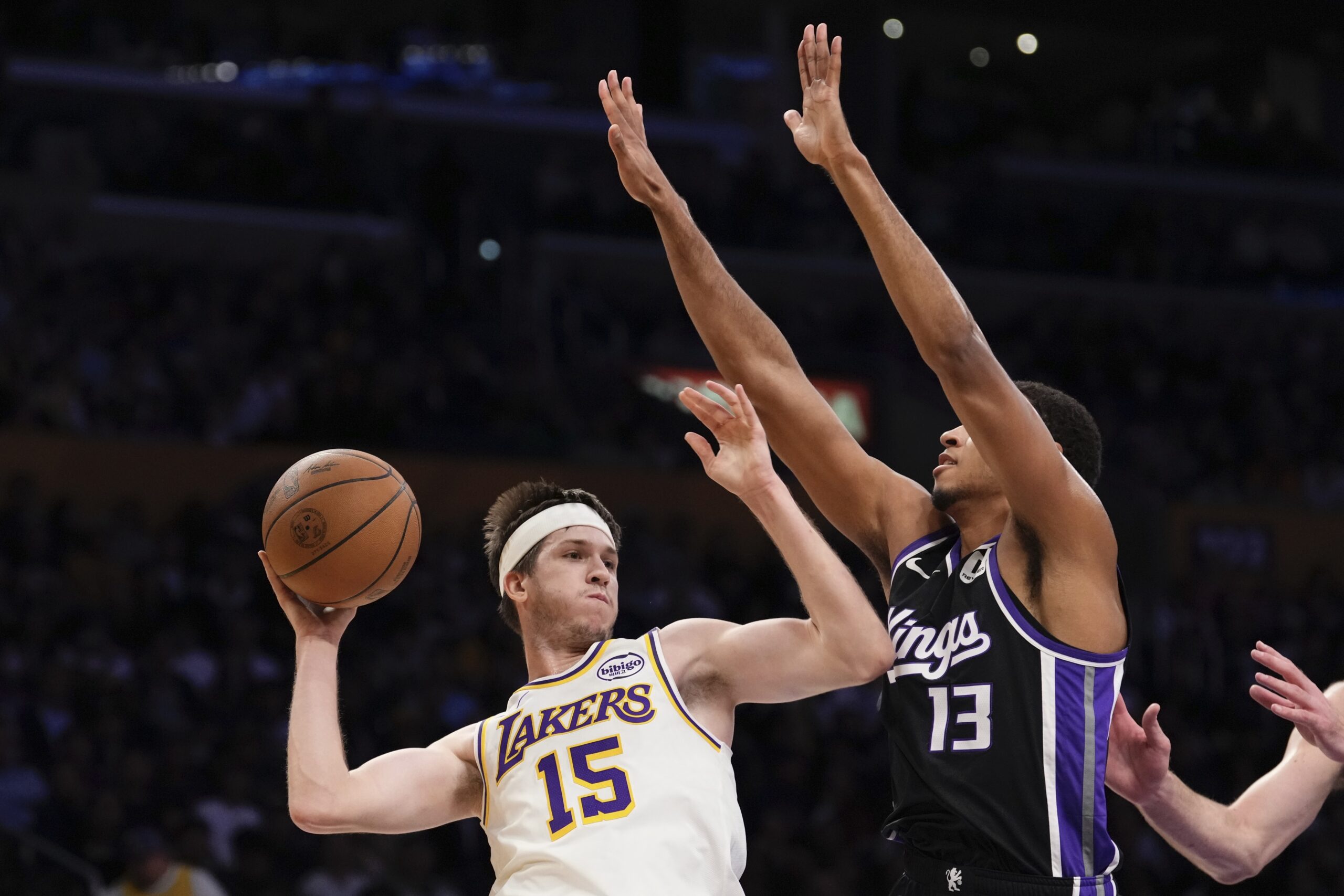 Lakers guard Austin Reaves, left, passes while under pressure from...