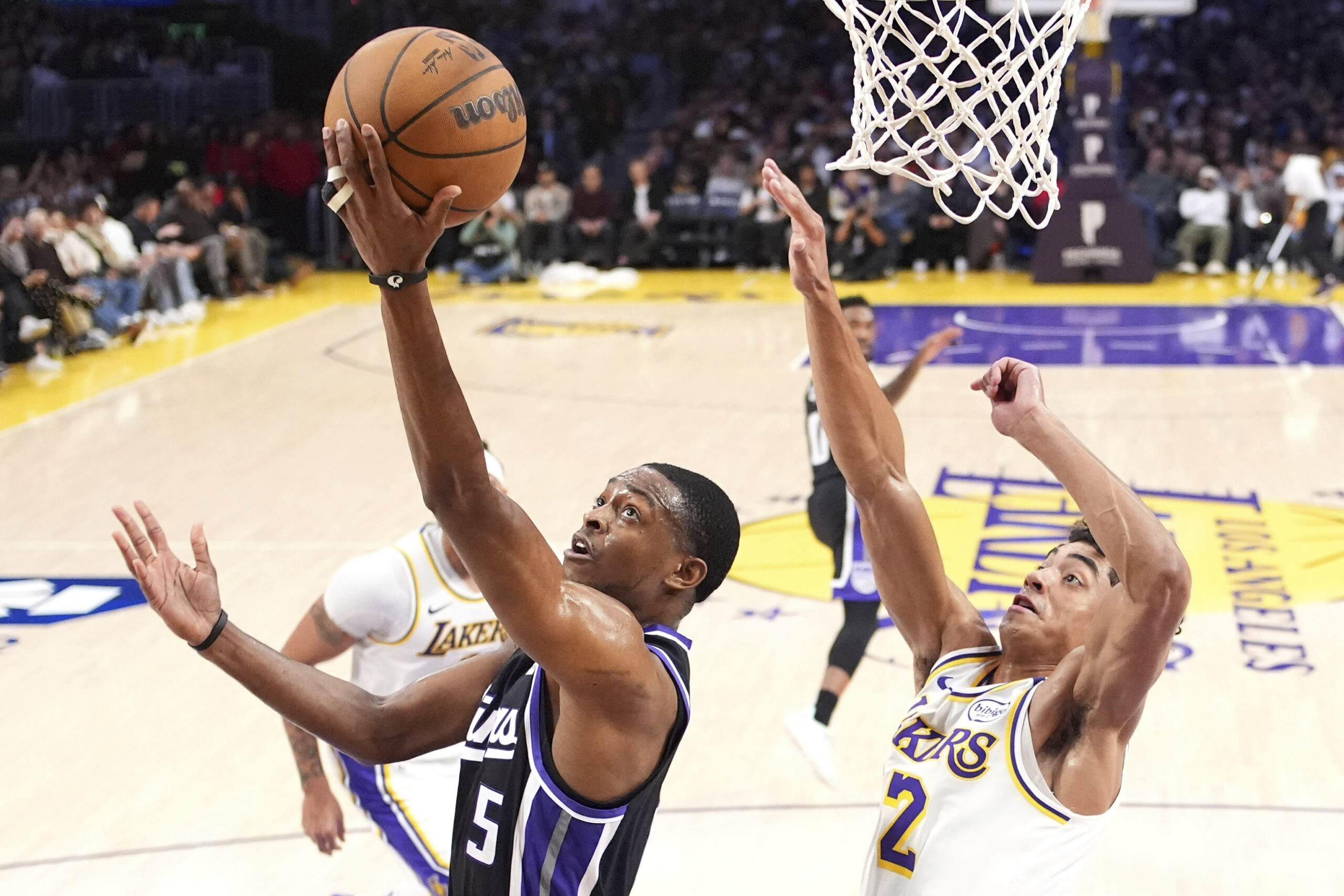 Sacramento Kings guard De’Aaron Fox, left, shoots as Lakers guard...