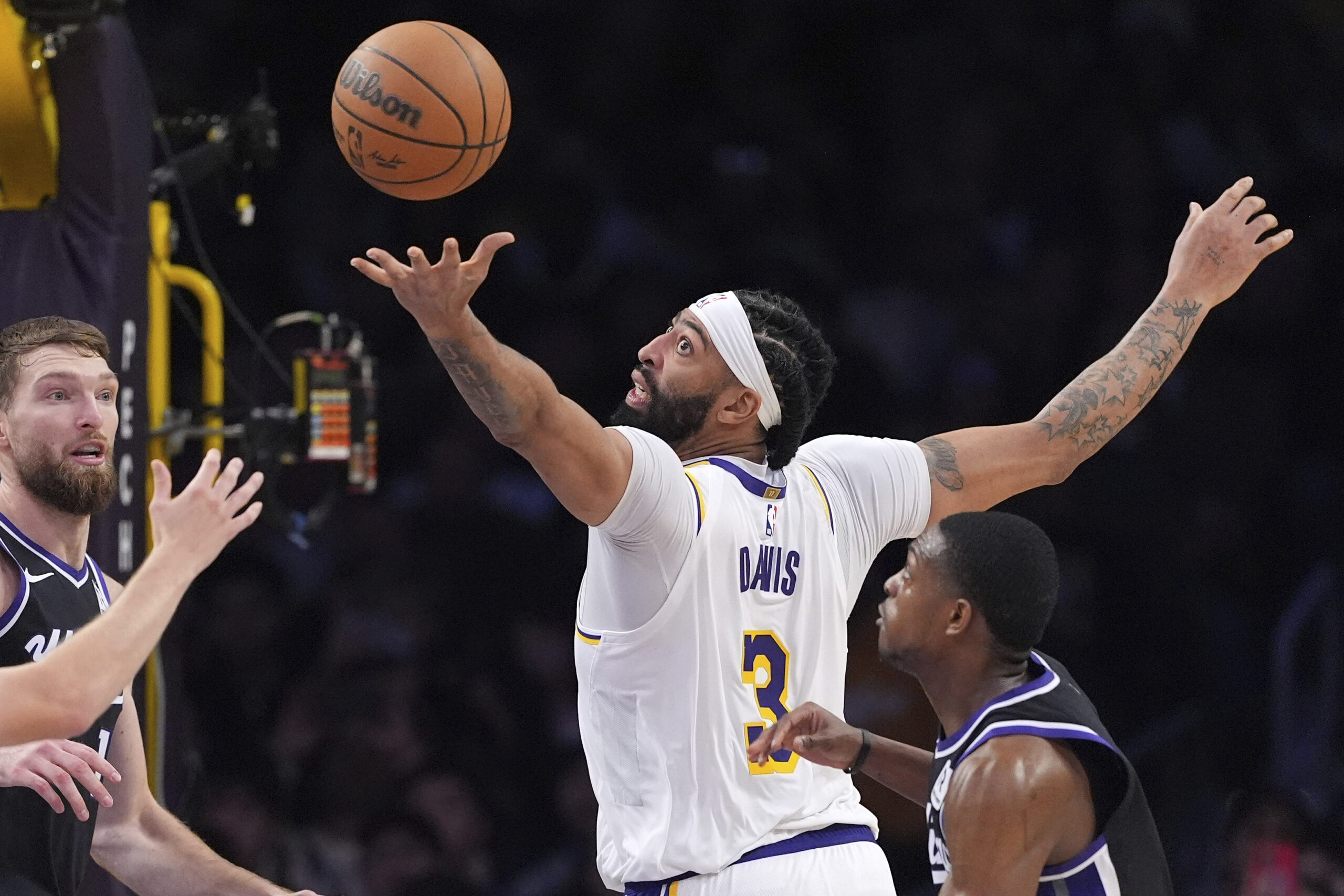 Lakers forward Anthony Davis, center, reaches for a loose ball...