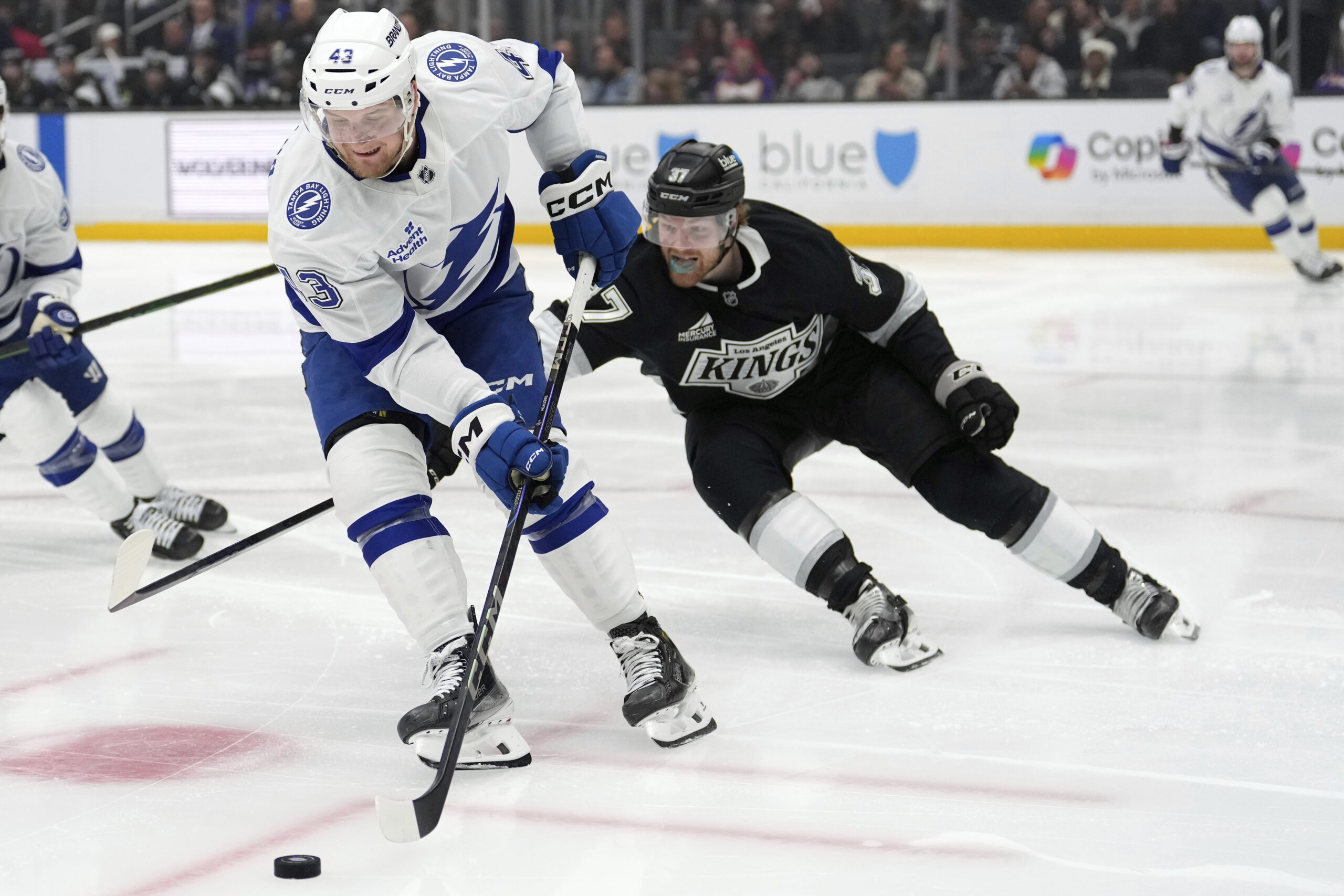 Tampa Bay Lightning defenseman Darren Raddysh, left, moves the puck...