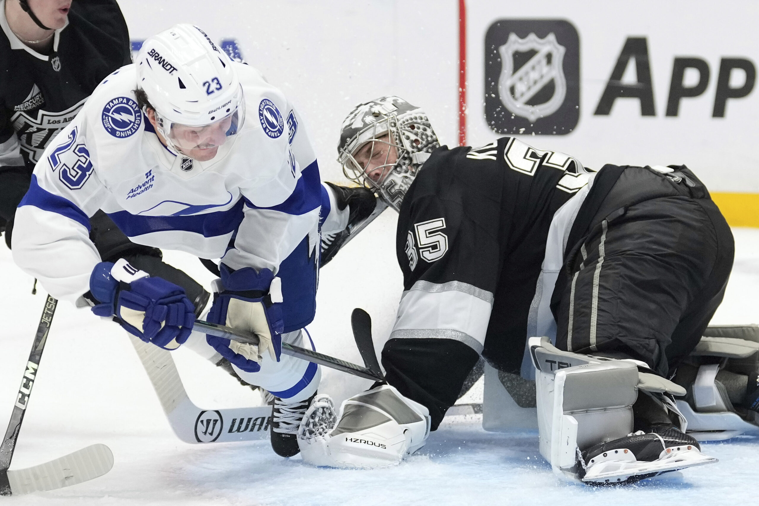 Kings goaltender Darcy Kuemper, right, is hit in the mask...