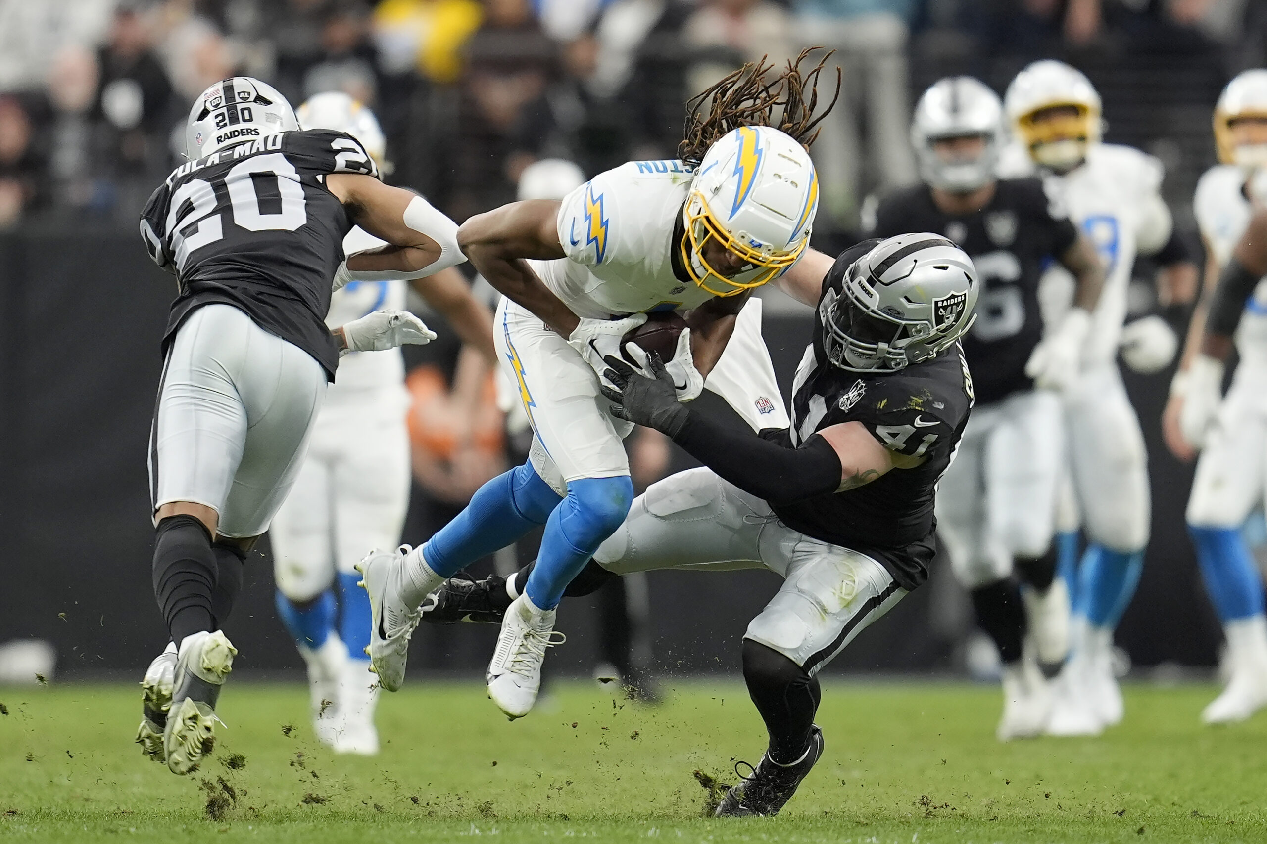 Los Angeles Chargers wide receiver Quentin Johnston, middle, runs against...