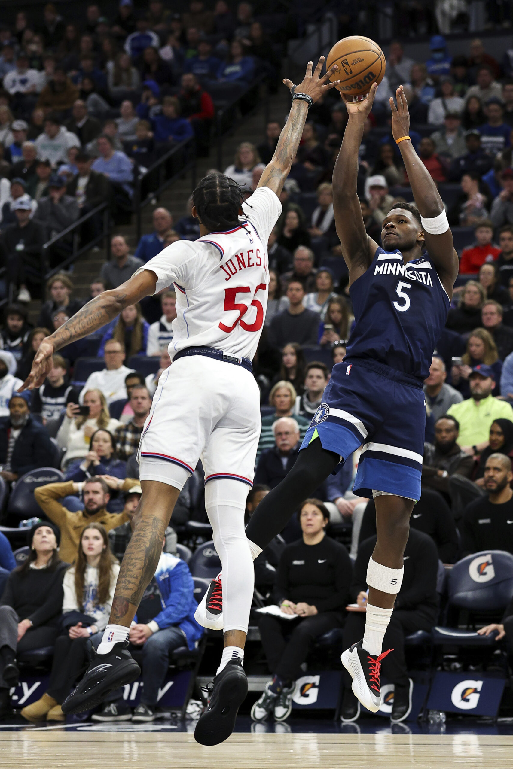 Minnesota Timberwolves guard Anthony Edwards, right, goes up to shoot...