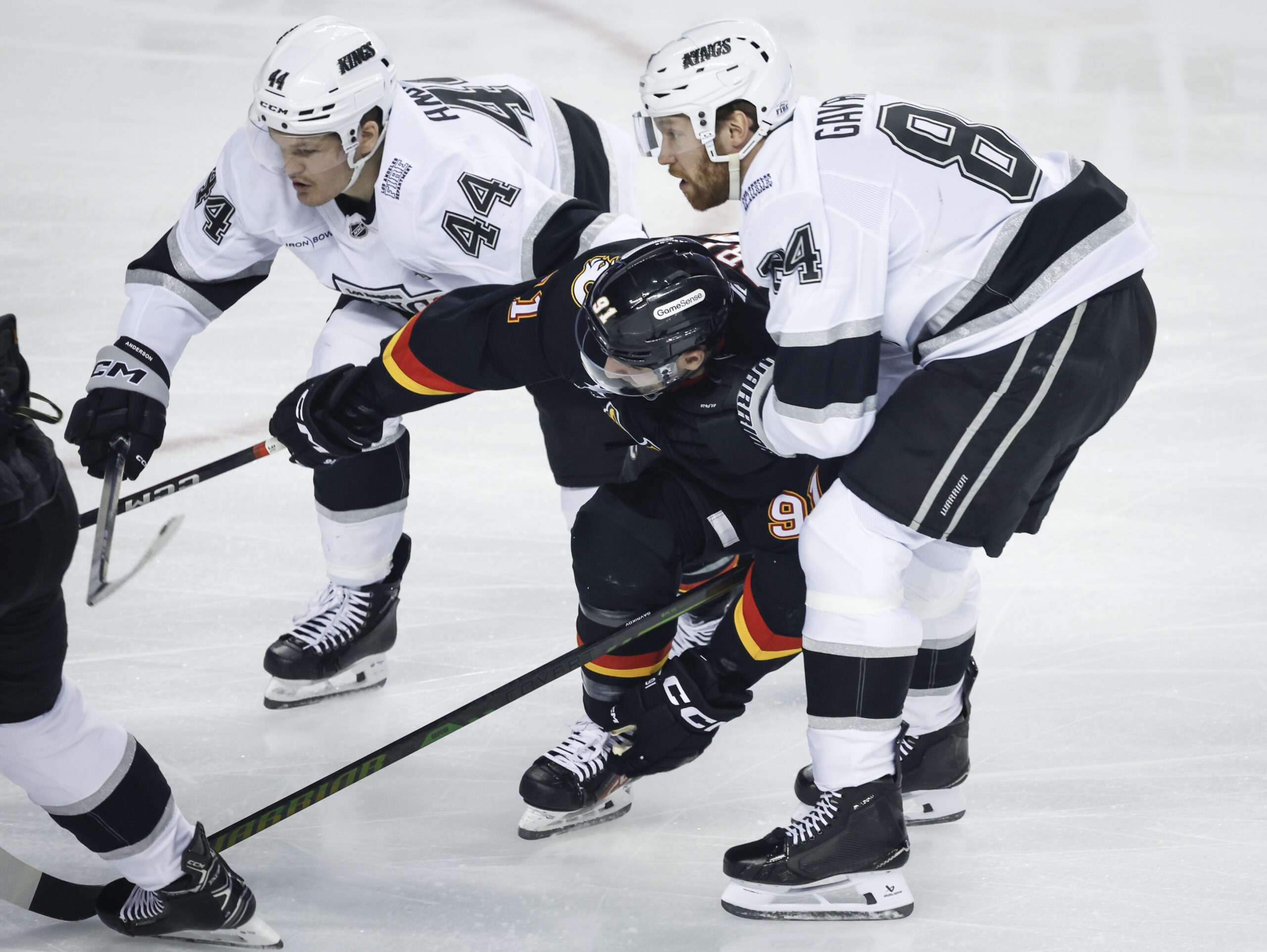 Kings’ Mikey Anderson (44) and Vladislav Gavrikov, right, check Calgary...