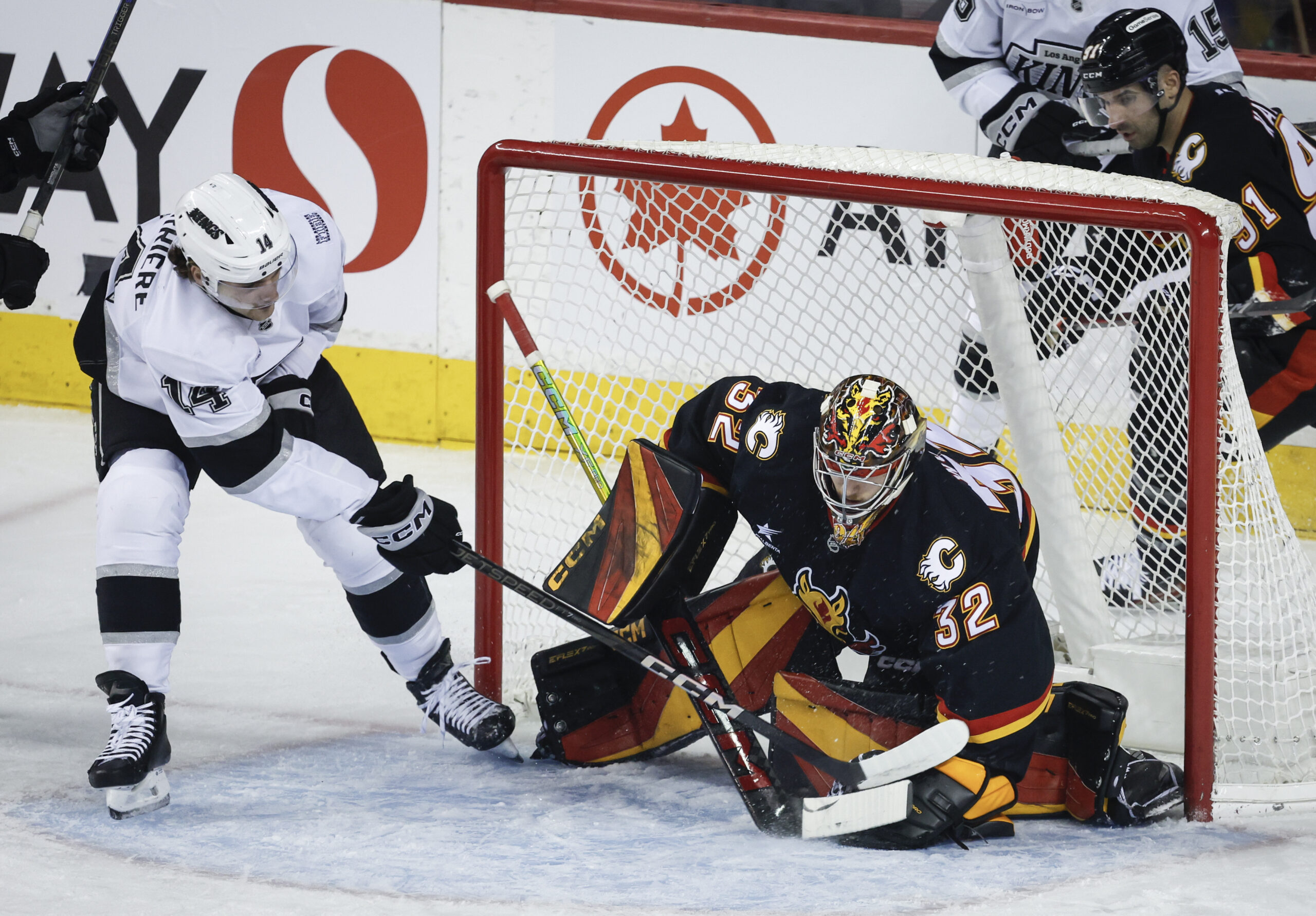 Kings’ Alex Laferriere, left, digs for the puck as Calgary...