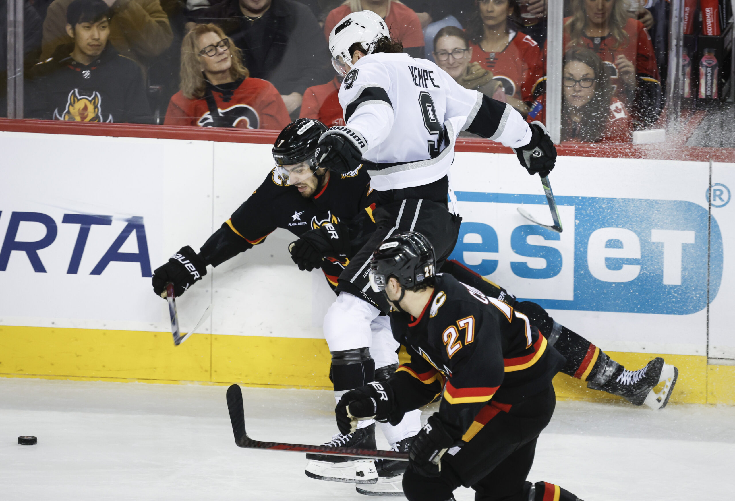 Kings’ Adrian Kempe, center, checks Calgary Flames’ Kevin Bahl, left,...