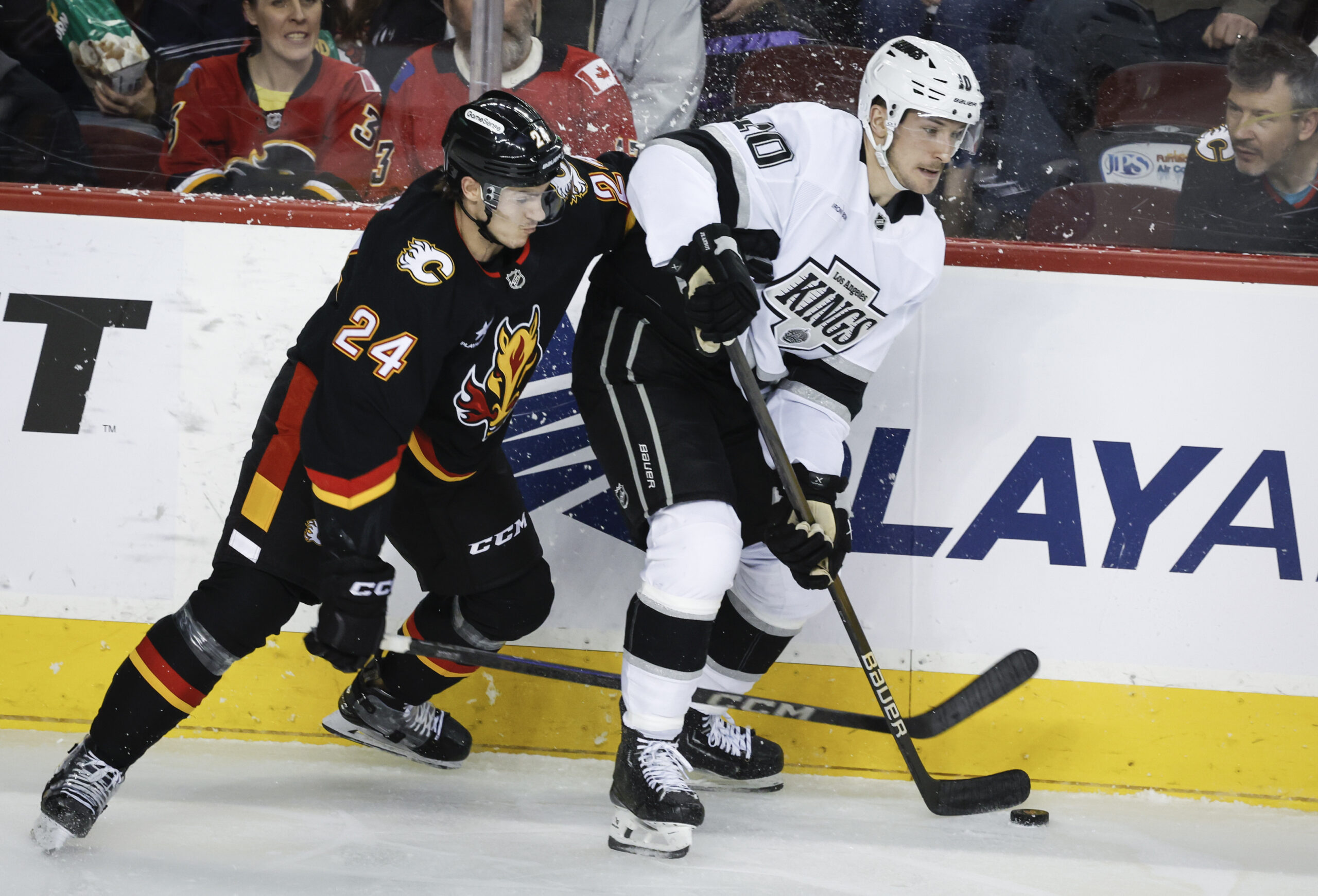 Kings’ Tanner Jeannot, right, is checked by Calgary Flames’ Jake...