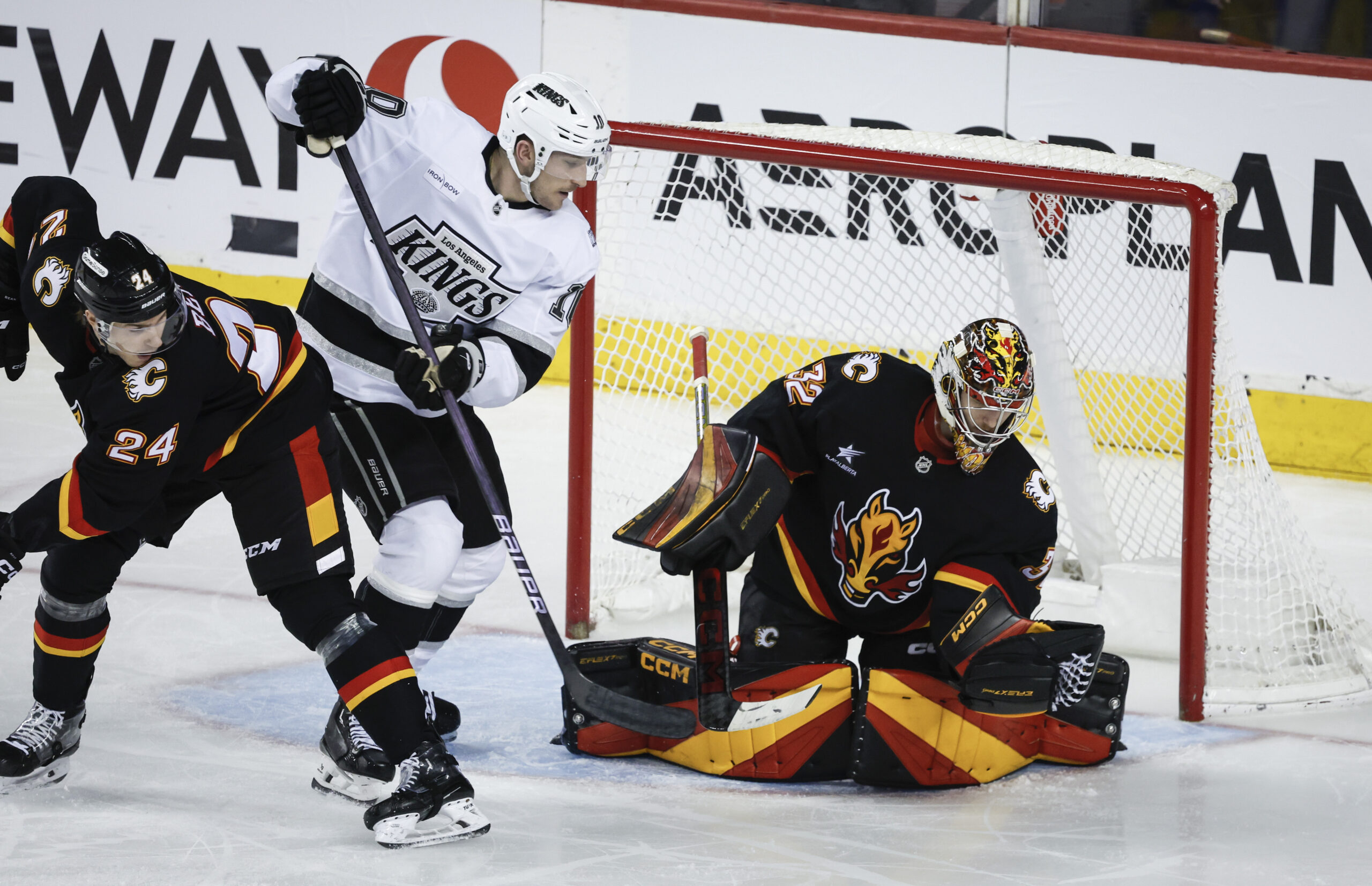 Kings’ Tanner Jeannot, center, is checked by Calgary Flames’ Jake...