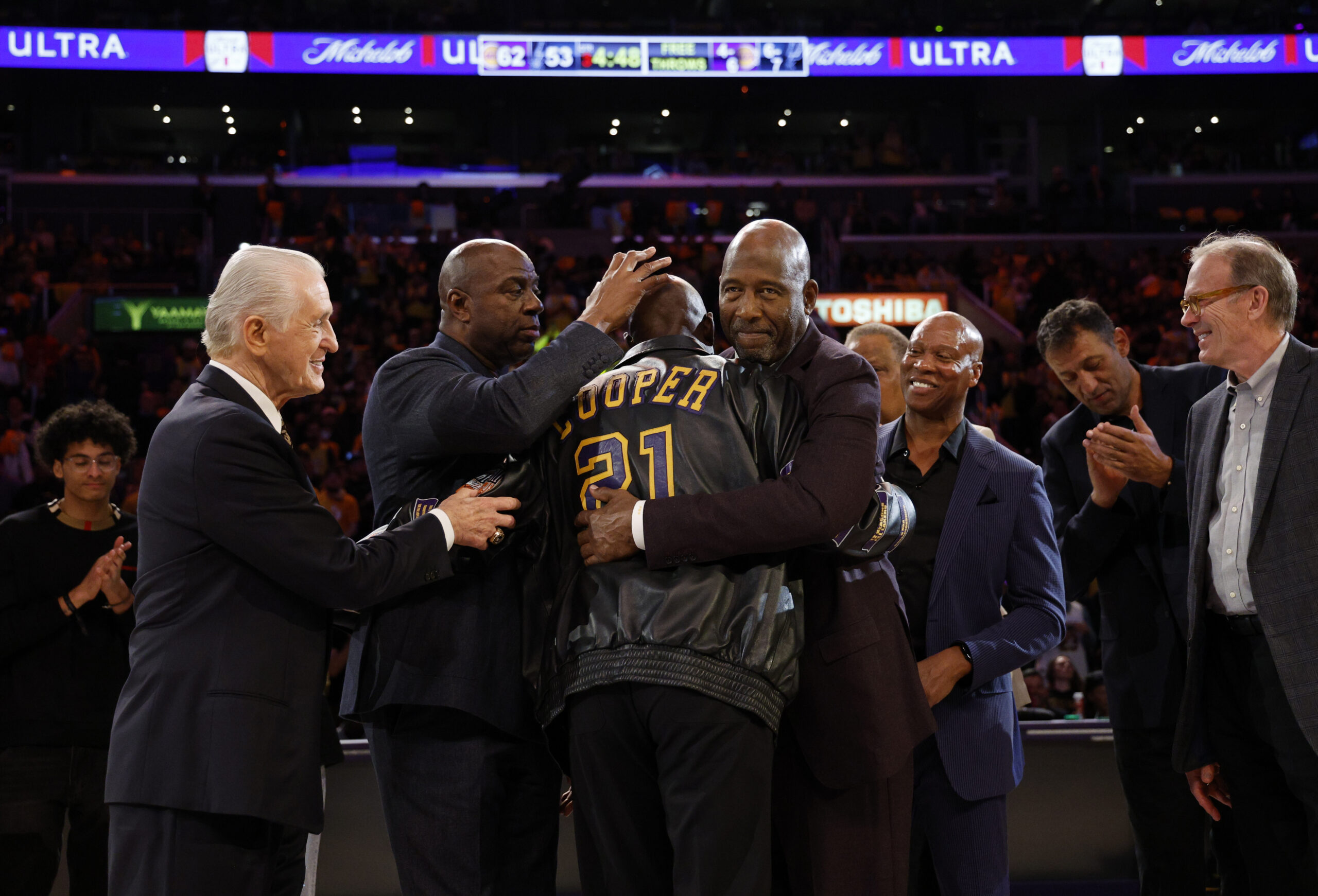 Former Lakers player Michael Cooper, center, is mobbed by former...